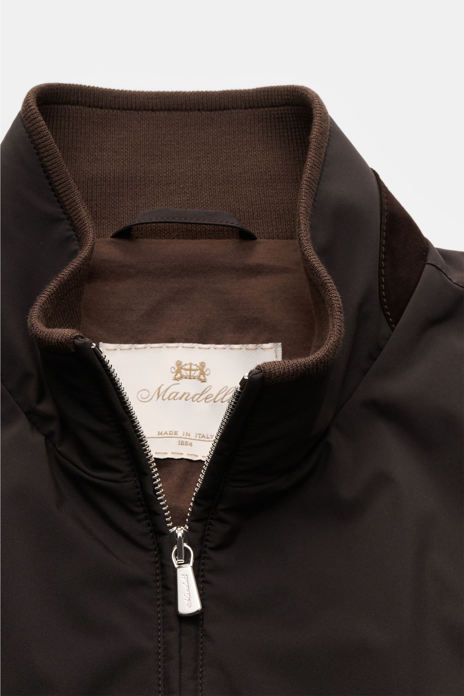 Close-up front view of the Mandelli Blouson dark brown showing the high-closing standing collar, soft microfibre, goat suede trim, and robust two-way zip. A perfect symbiosis of luxury and comfort: This blouson by MANDELLI is confidently elegant and effor
