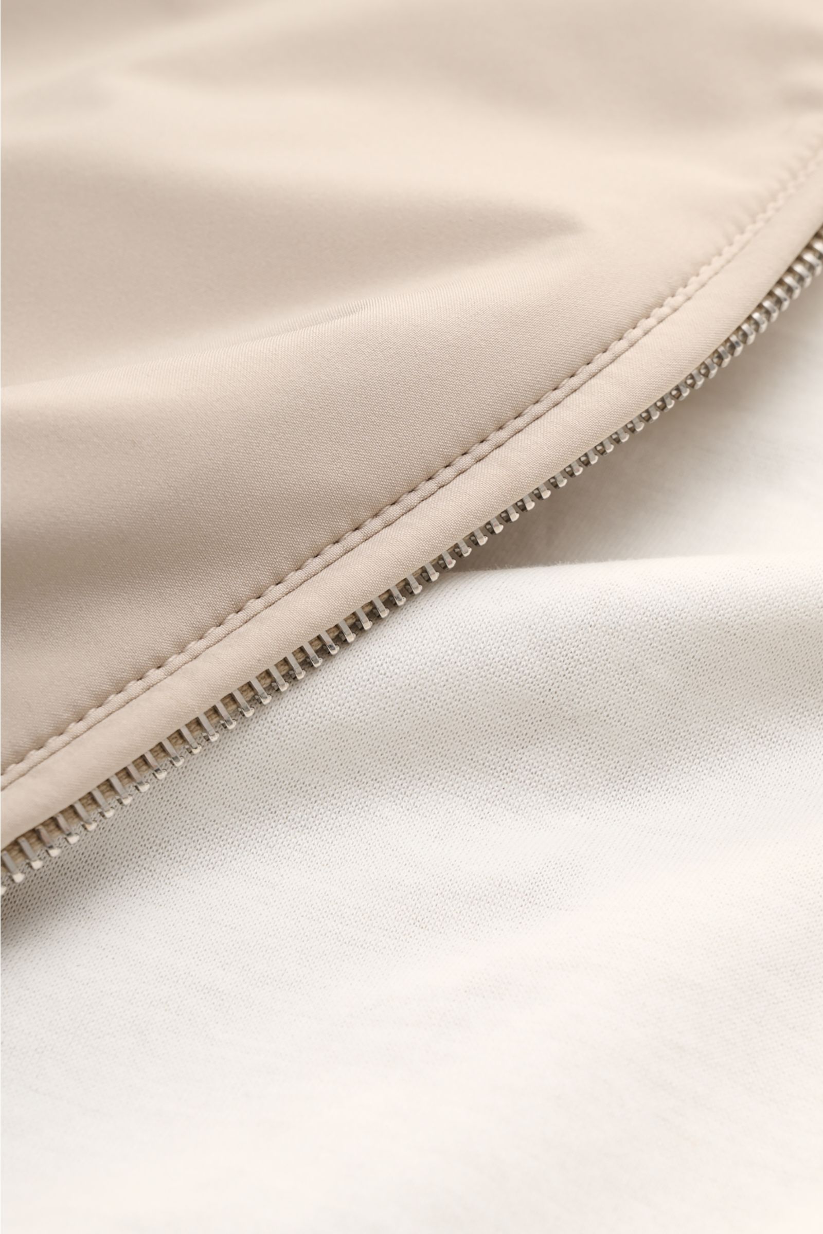 Close-up detail of the beige Mandelli Blouson showing the high-quality microfibre fabric, smooth lining, and robust silver zipper from a side angle. A perfect symbiosis of luxury and comfort: This blouson by MANDELLI is confidently elegant and effortlessl