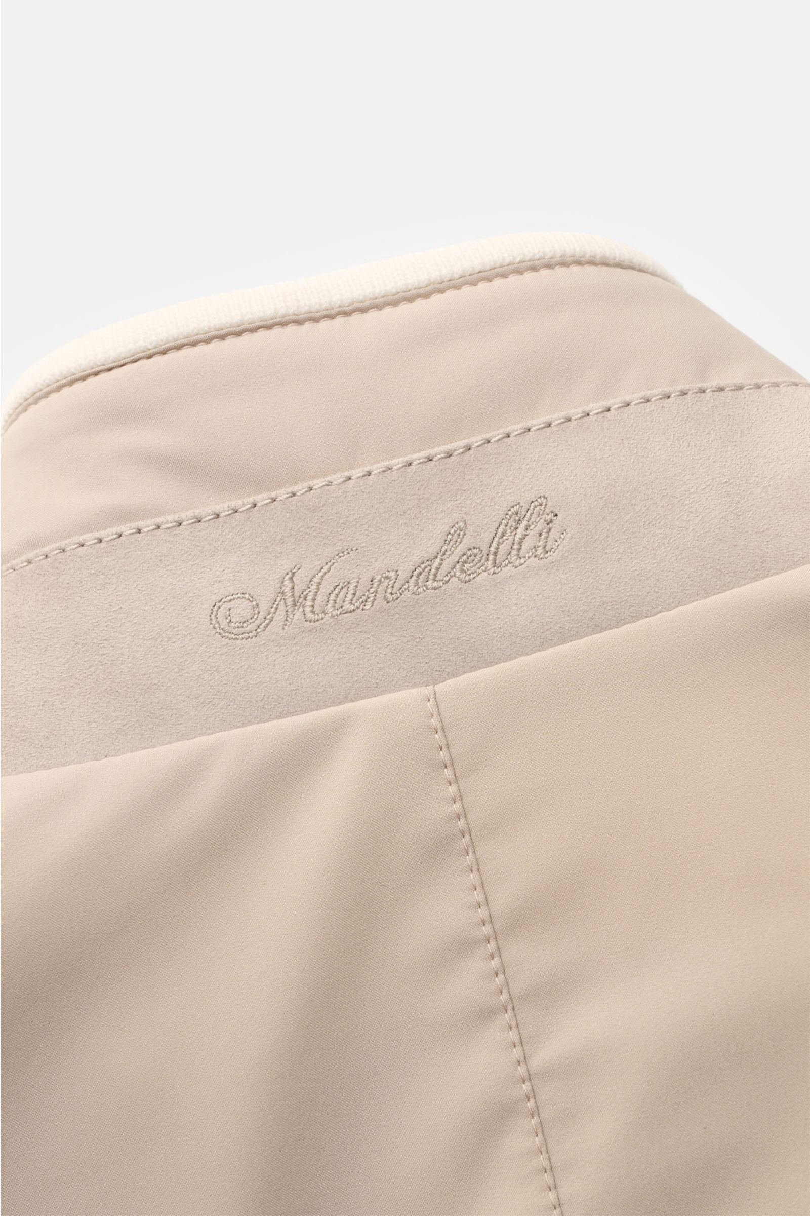 Close-up rear view of Mandelli Blouson beige showing high-quality microfibre, goat suede trim, and embroidered logo on the collar; a perfect symbiosis of luxury and comfort for mild days with slim fit, robust two-way zip, high-closing standing collar, hip