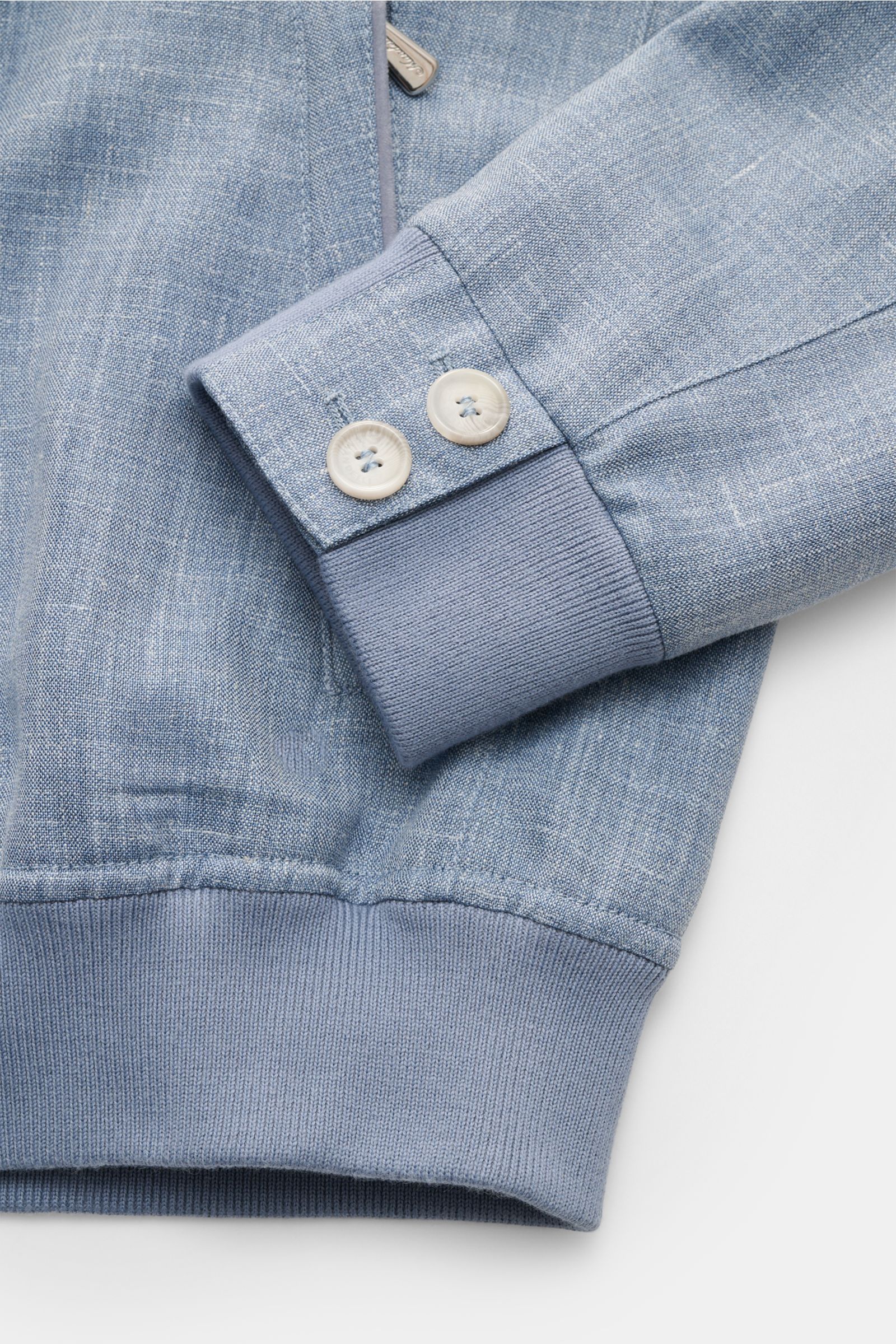 Close-up front view of the Mandelli Blouson smoky blue mottled sleeve cuff showing buttons, ribbed elastic hem, and soft virgin wool, silk, linen blend fabric. Confident ease for the transitional period: Its luxurious character makes this blouson by MANDE