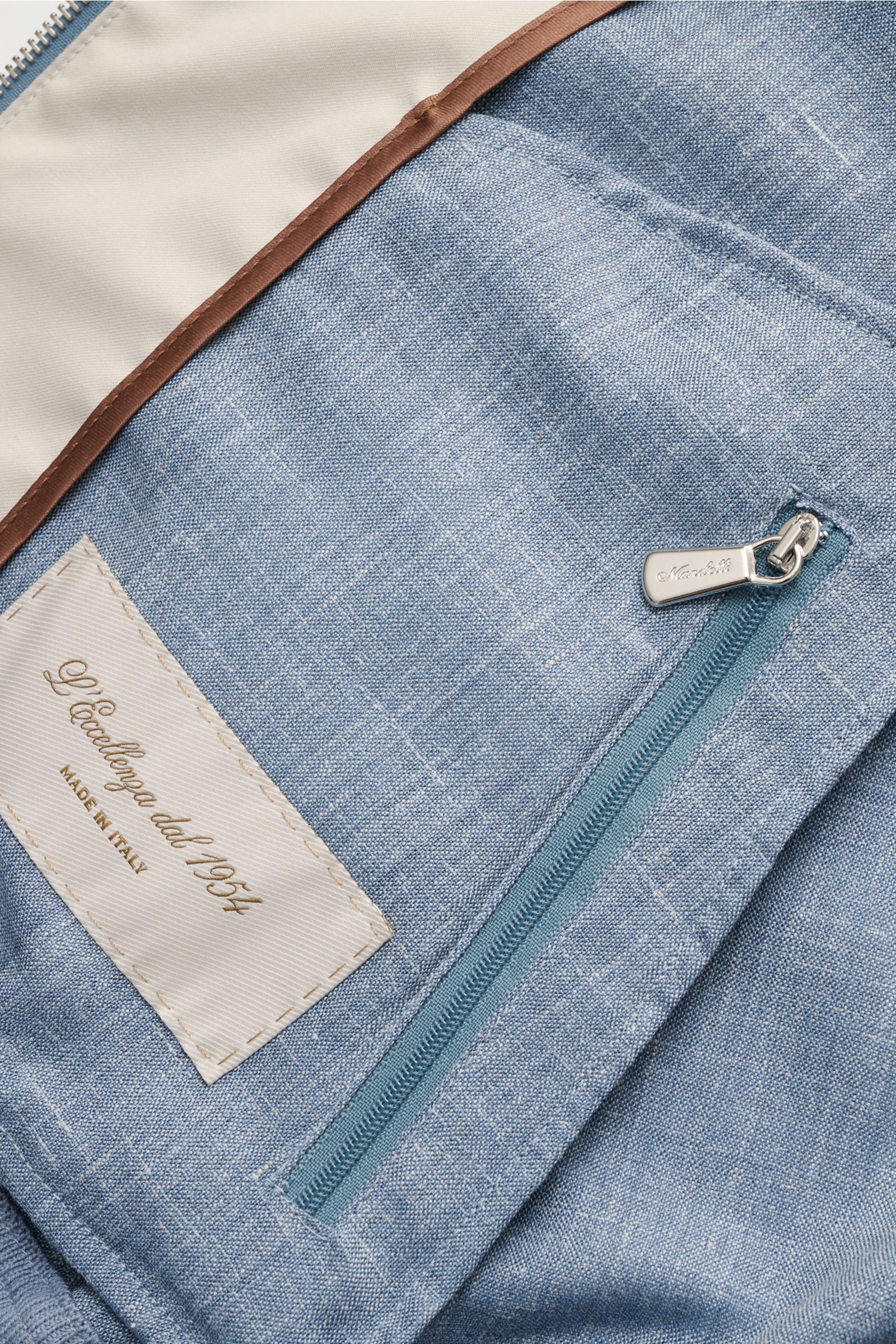 Close-up inside view of the Mandelli Blouson smoky blue mottled showing soft virgin wool, silk, linen blend, two-way zip, elastic cuffs, standing collar, and label.