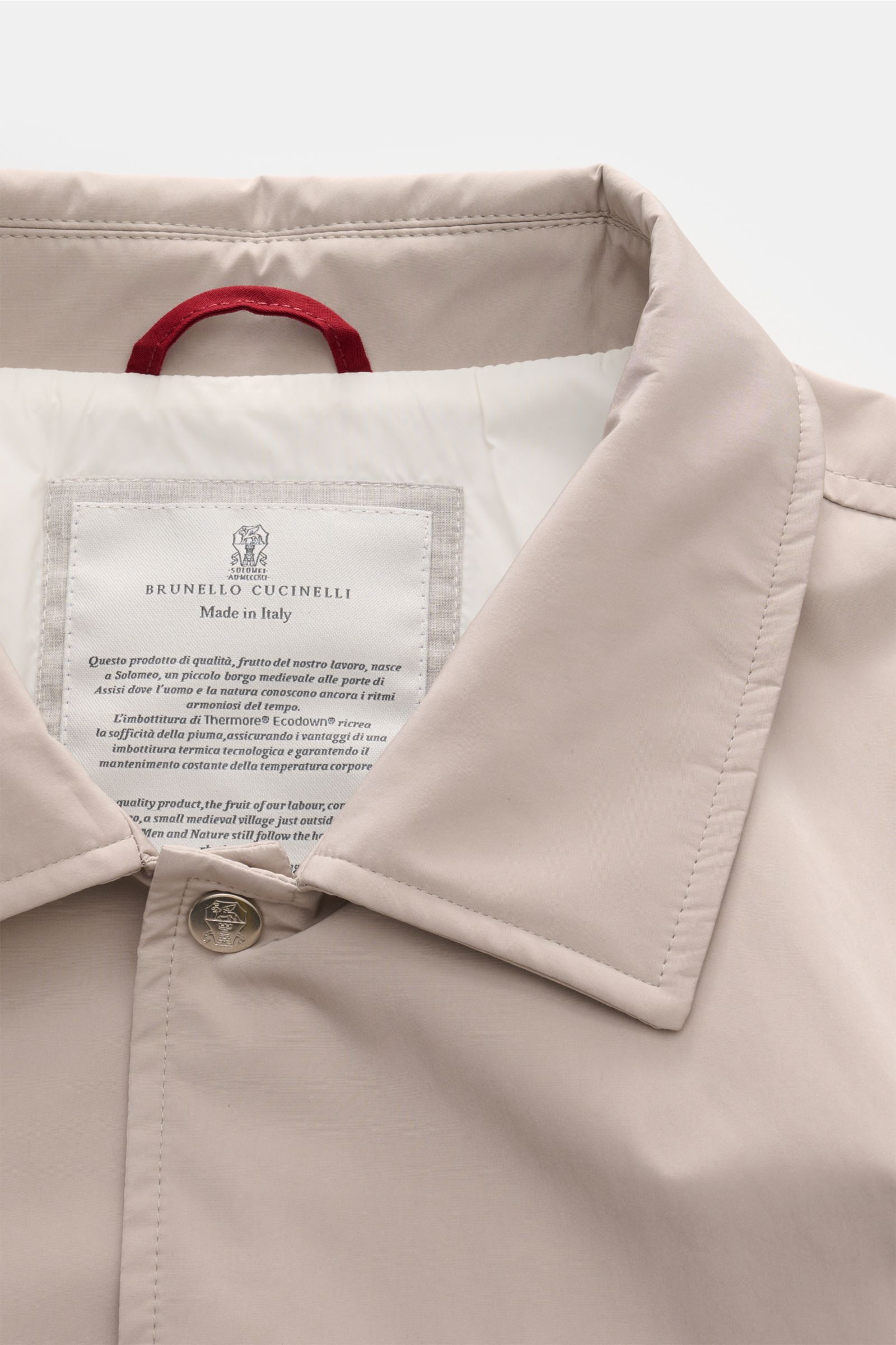 Close-up front top view of the Brunello Cucinelli Jacke sand, showcasing the soft microfaser fabric, umlegekragen collar, and metal snap button with label inside. 