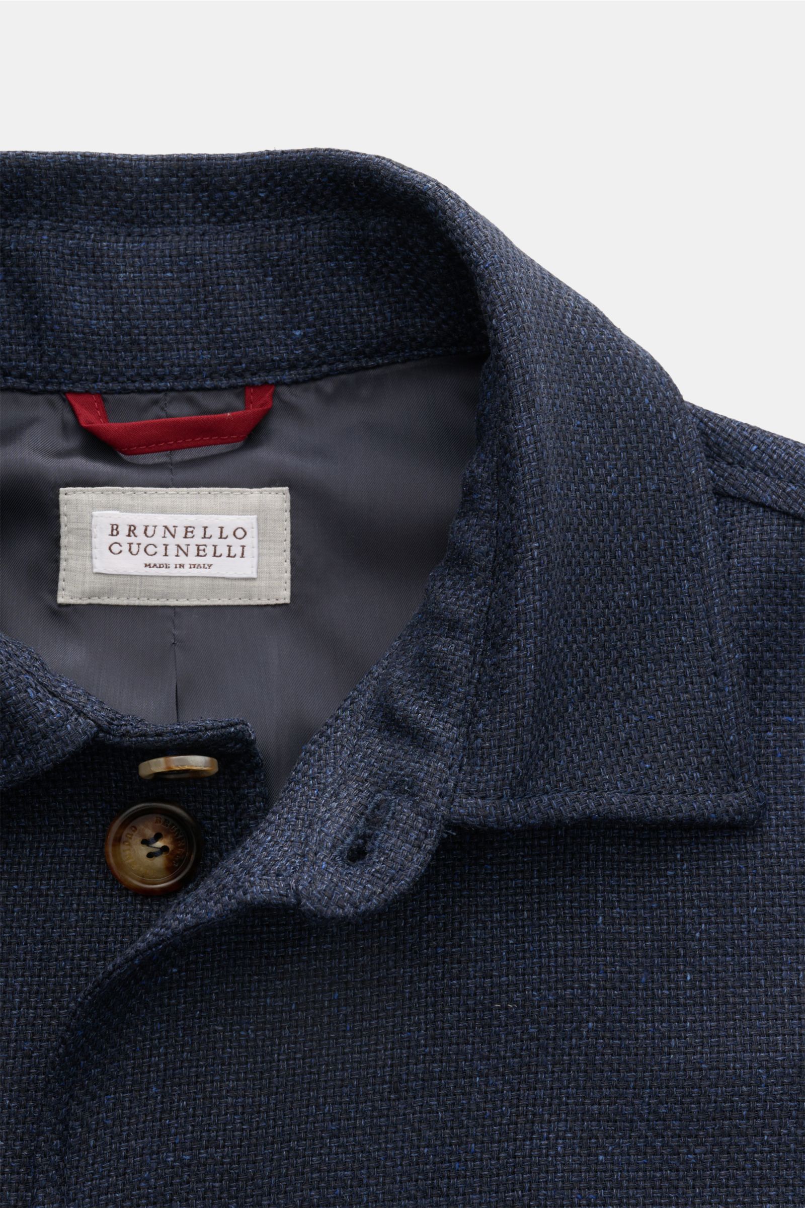 Close-up front view of the collar and label of the Brunello Cucinelli Blouson navy mottled, showcasing its distinctive three-dimensional weave and fine blend of silk, linen, and wool. Lightweight and elegant with a slim fit, seven-button placket, turn-dow
