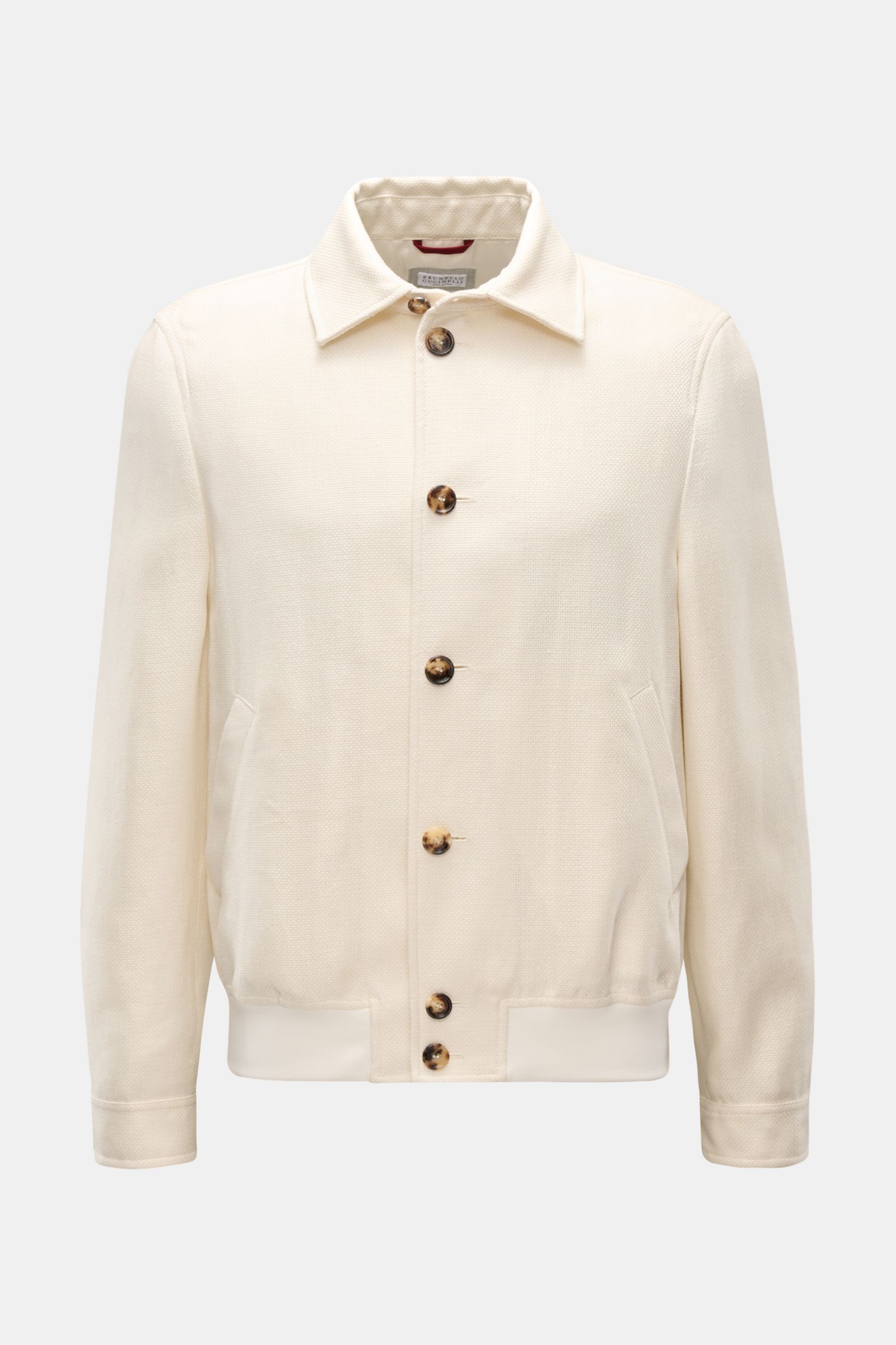 Front view of the Brunello Cucinelli Blouson creme, a slim fit jacket with seven-button placket, silk, linen, and wool mix, soft textured fabric, angled flap pockets, cuffed sleeves, elastic hem, and natural elegance from its distinctive three-dimensional