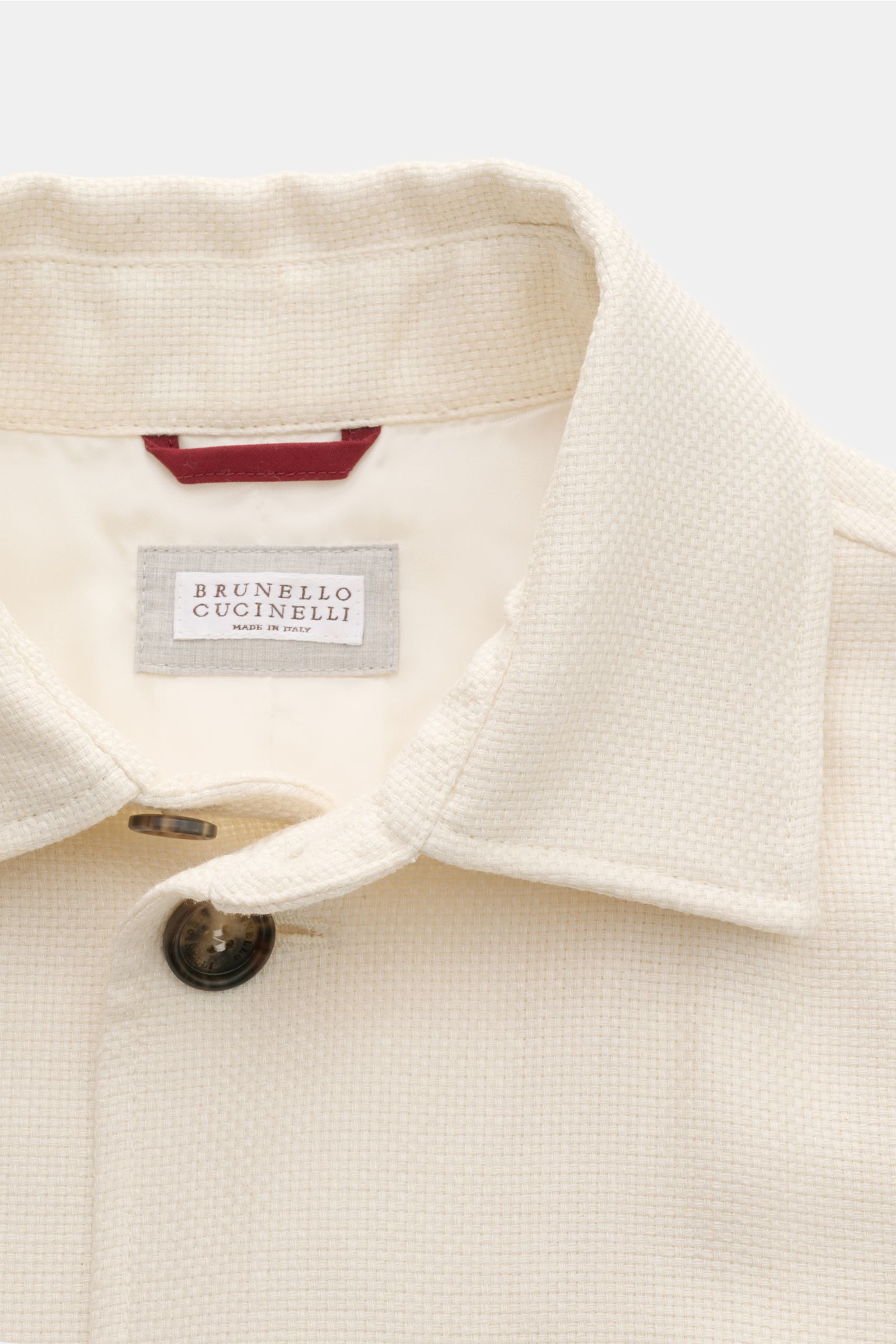Close-up front view of the Brunello Cucinelli Blouson cream showing the textured silk, linen, and wool blend fabric, turn-down collar, and seven-button placket, highlighting its lightweight elegance and distinctive weave.