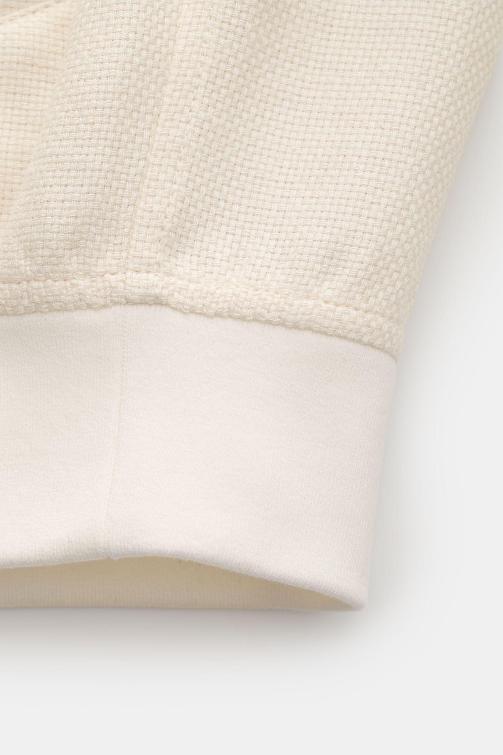 Close-up front view of the cream textured hem and cuff of the Brunello Cucinelli Blouson cream, lightweight silk, linen, wool blend.