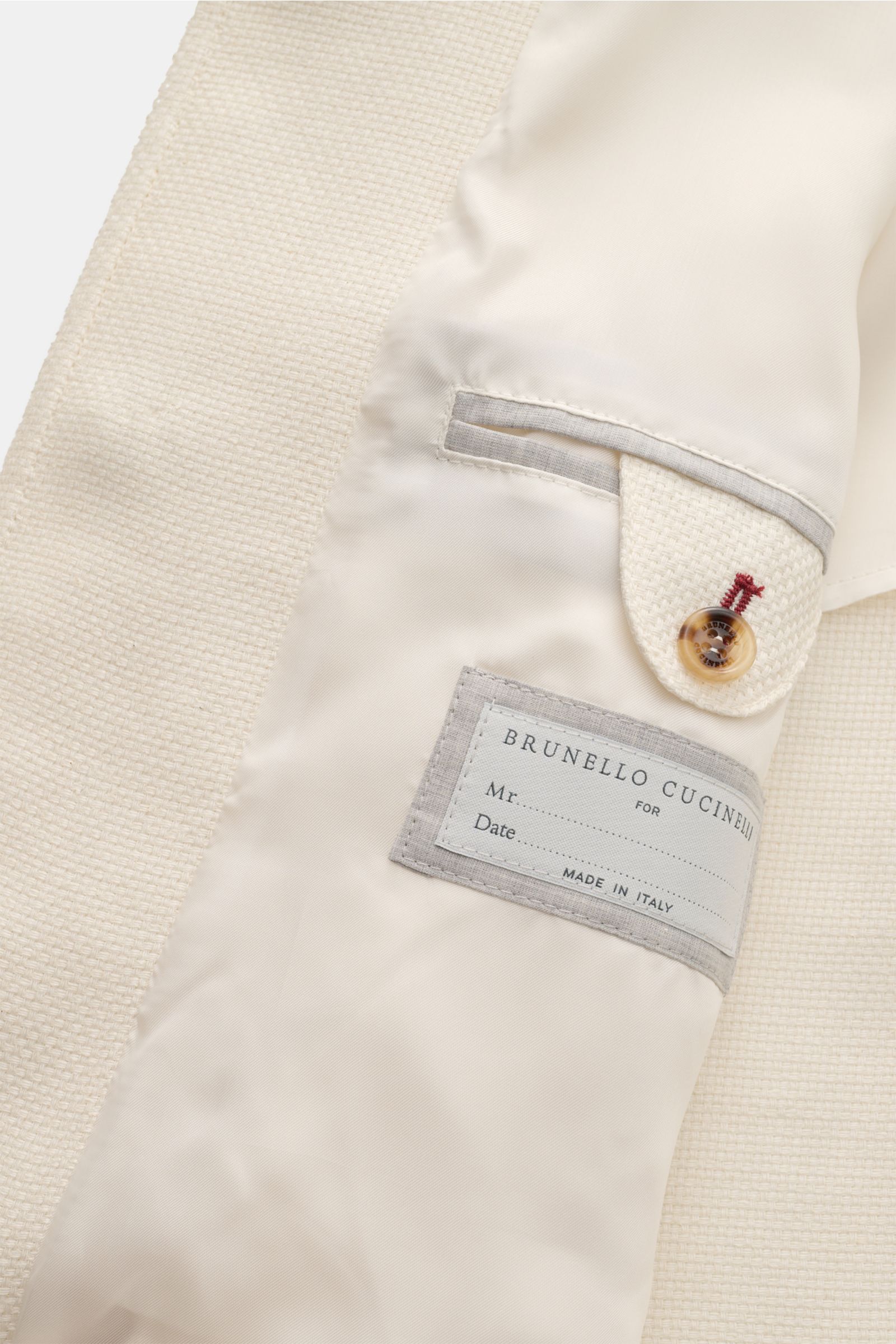 Close-up interior view of the Brunello Cucinelli Blouson creme showcasing the cream-colored silk, linen, and wool blend fabric with a soft, slightly textured feel, slim fit seven-button placket, turn-down collar, slanted flap pockets with snap buttons, cu