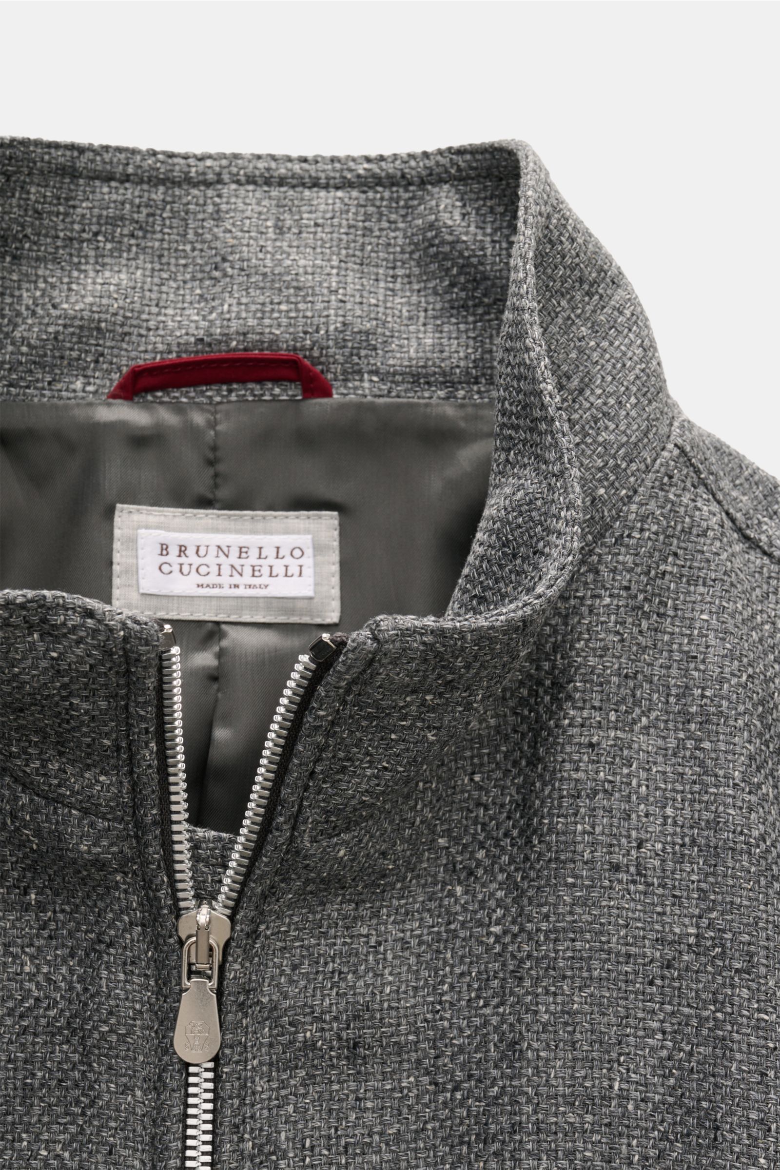 Close-up front view of the collar and zipper of the Brunello Cucinelli Blouson sand meliert, showcasing its textured linen-wool-silk blend fabric with denim look and contrast lining. Luxus in jedem Detail: Von der Wahl des Mischgewebes aus Leinen und W