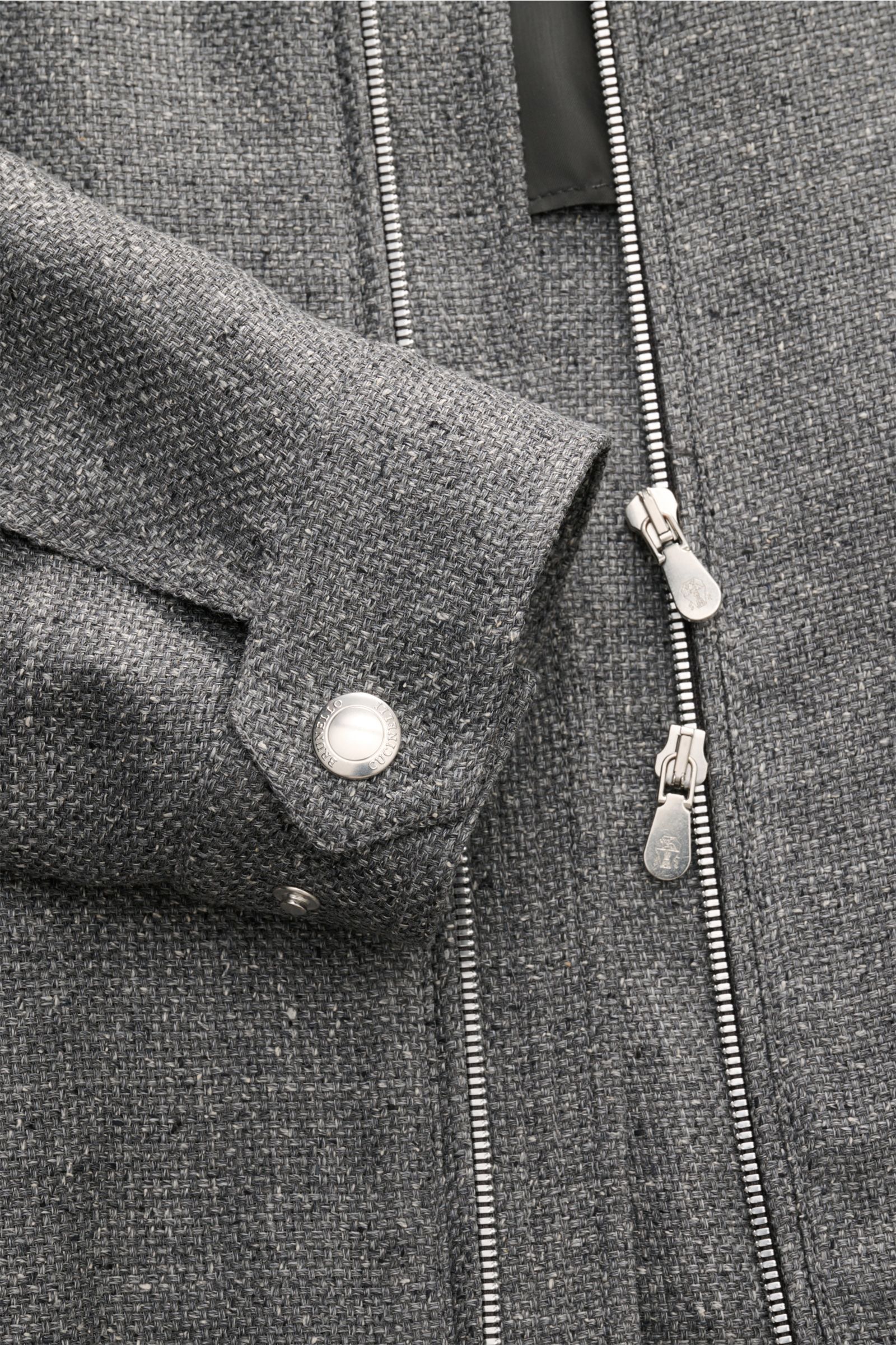 Close-up front view of the Brunello Cucinelli Blouson sand meliert, showcasing its textured wool, cashmere, and silk blend fabric with denim look, two-way zipper, snap-button cuff, and contrast lining. Luxus in jedem Detail: Von der Wahl des Mischgewebes 