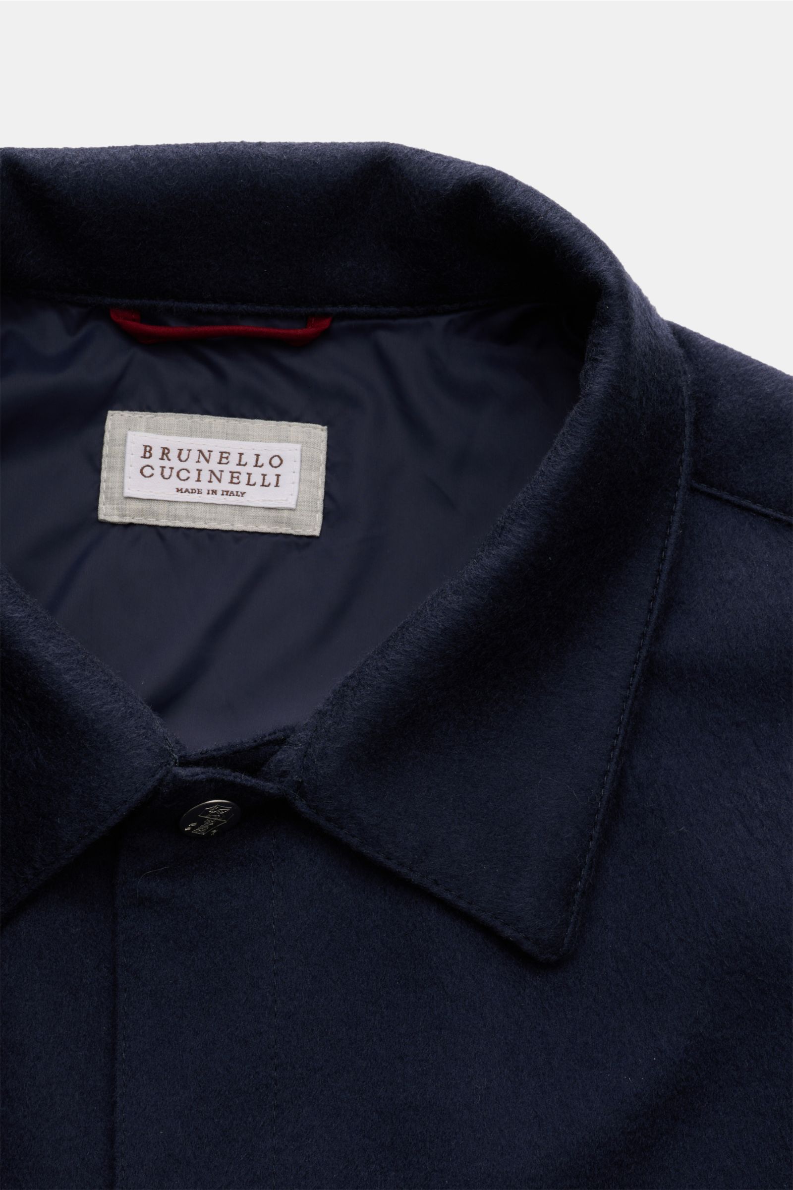 Close-up top view of the Brunello Cucinelli Cashmere Jacke navy, showcasing its soft collar, button, and interior label.


