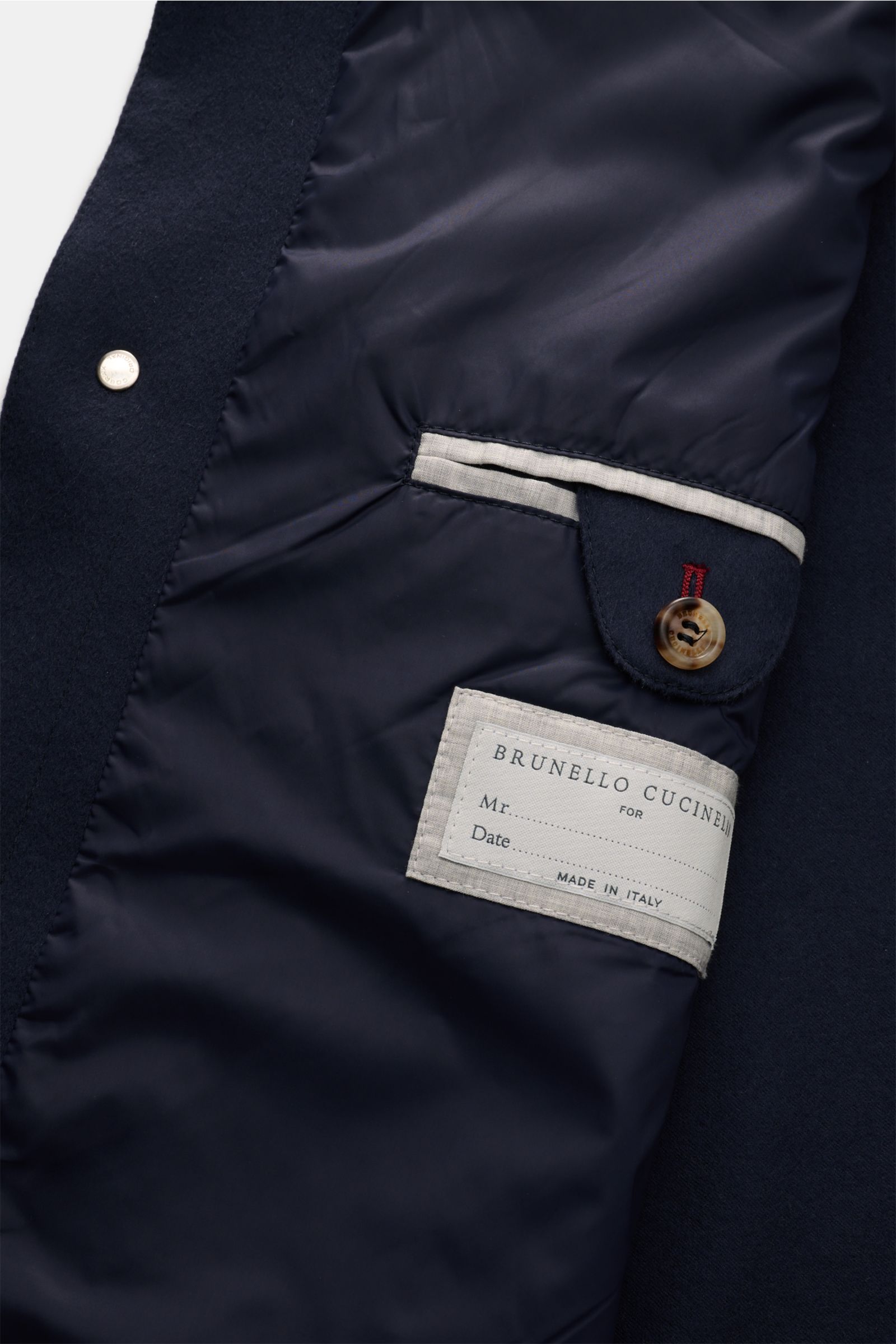 Close-up inside view of the Brunello Cucinelli Cashmere Jacke navy showing the lining, buttoned inner pocket, and brand label made in Italy.

