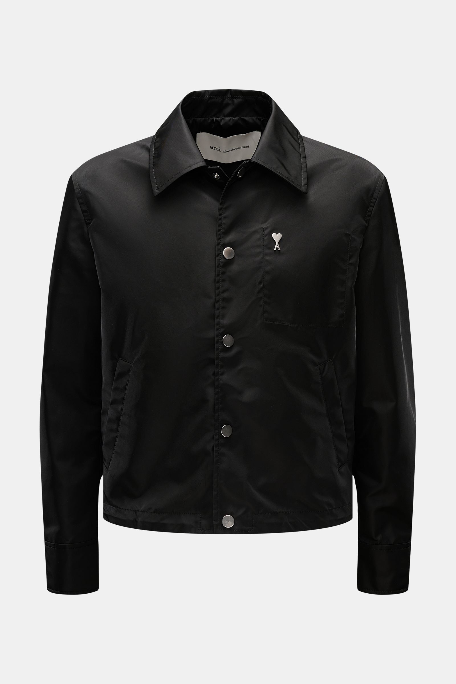 Front view of Ami Paris Jacke schwarz in black microfiber with regular fit, smooth texture, snap button placket, turn-down collar, logo on chest, piped front pockets with snaps, button cuffs, adjustable hem, unconstructed design, and one inside pocket.