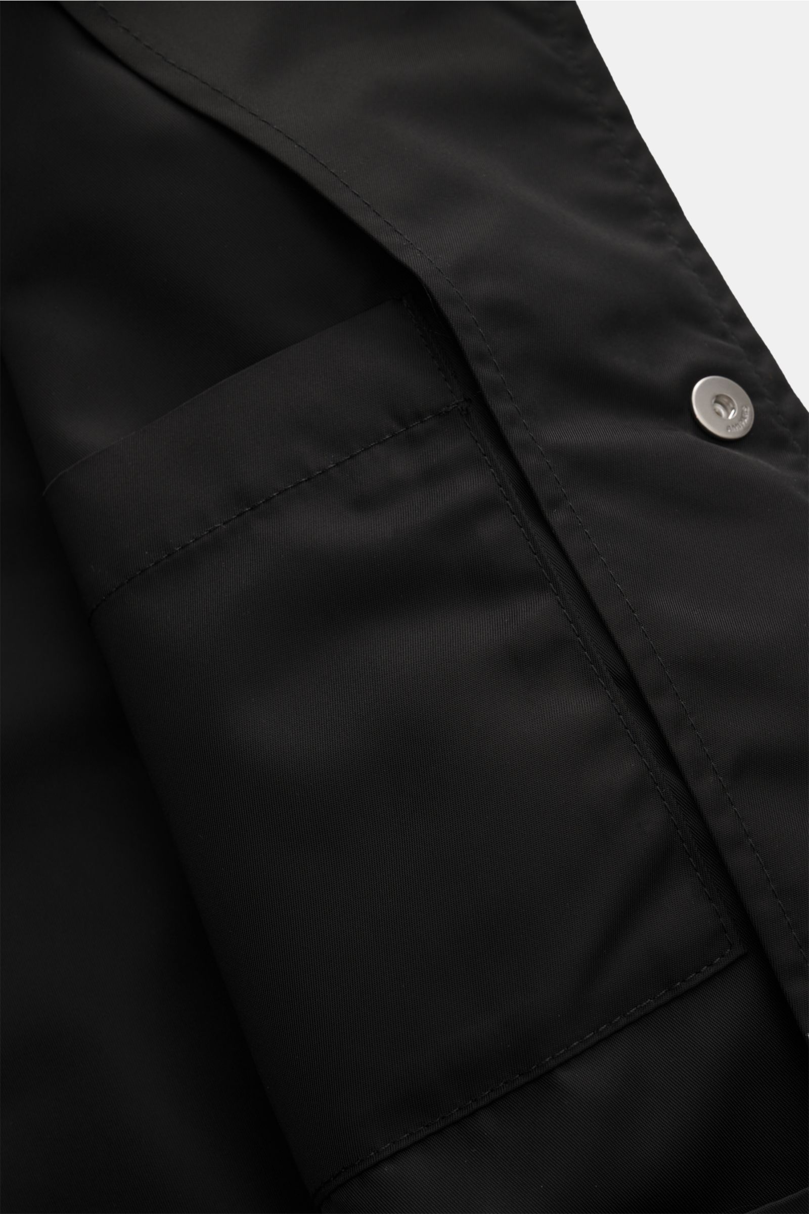 Close-up view of the inner pocket and snap button detail of the Ami Paris Jacke schwarz, made of high-quality microfiber with a smooth touch. Stylish and versatile transitional jacket with regular fit, snap button placket, turn-down collar, brand logo on 