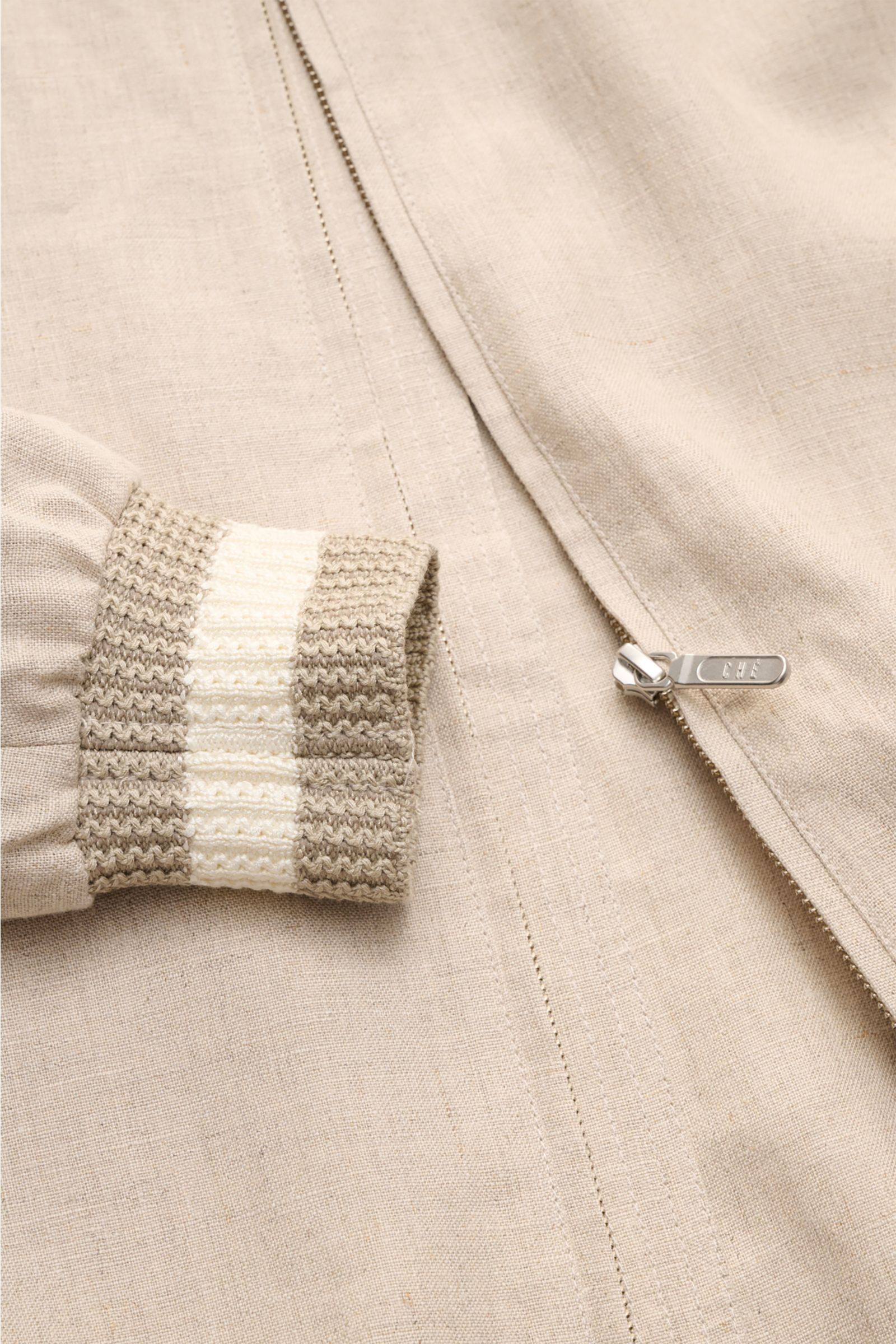 Ché Blouson 'Benito' beige meliert aus reinem Leinen, Slim Fit, halb gefüttert, mit Umlegekragen, robustem Reißverschluss, paspelierten Fronttaschen, elastischen Saum- und Ärmelbündchen, zwei Innentaschen; Detailaufnahme von Ärmelbündchen und Front.