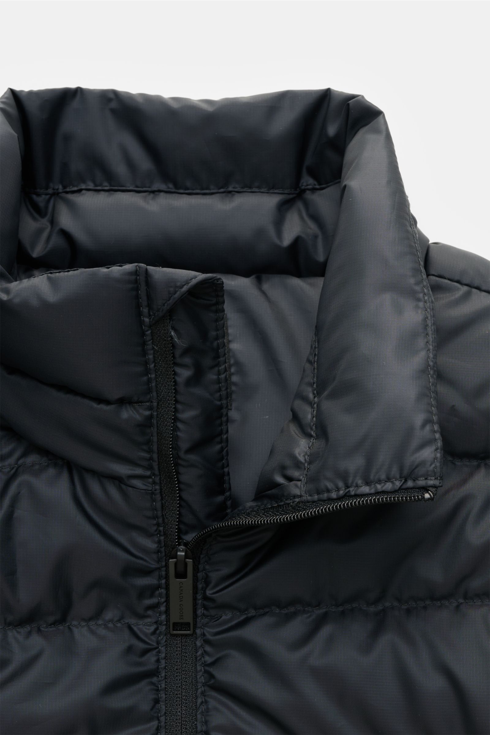 Close-up front view of the Canada Goose Down jacket 'Stratus Tonal' navy, showing the padded standing collar, robust two-way zip, and ripstop fabric with a smooth, wind and water repellent finish. 

The super lightweight 'Stratus Tonal' down jacket by 