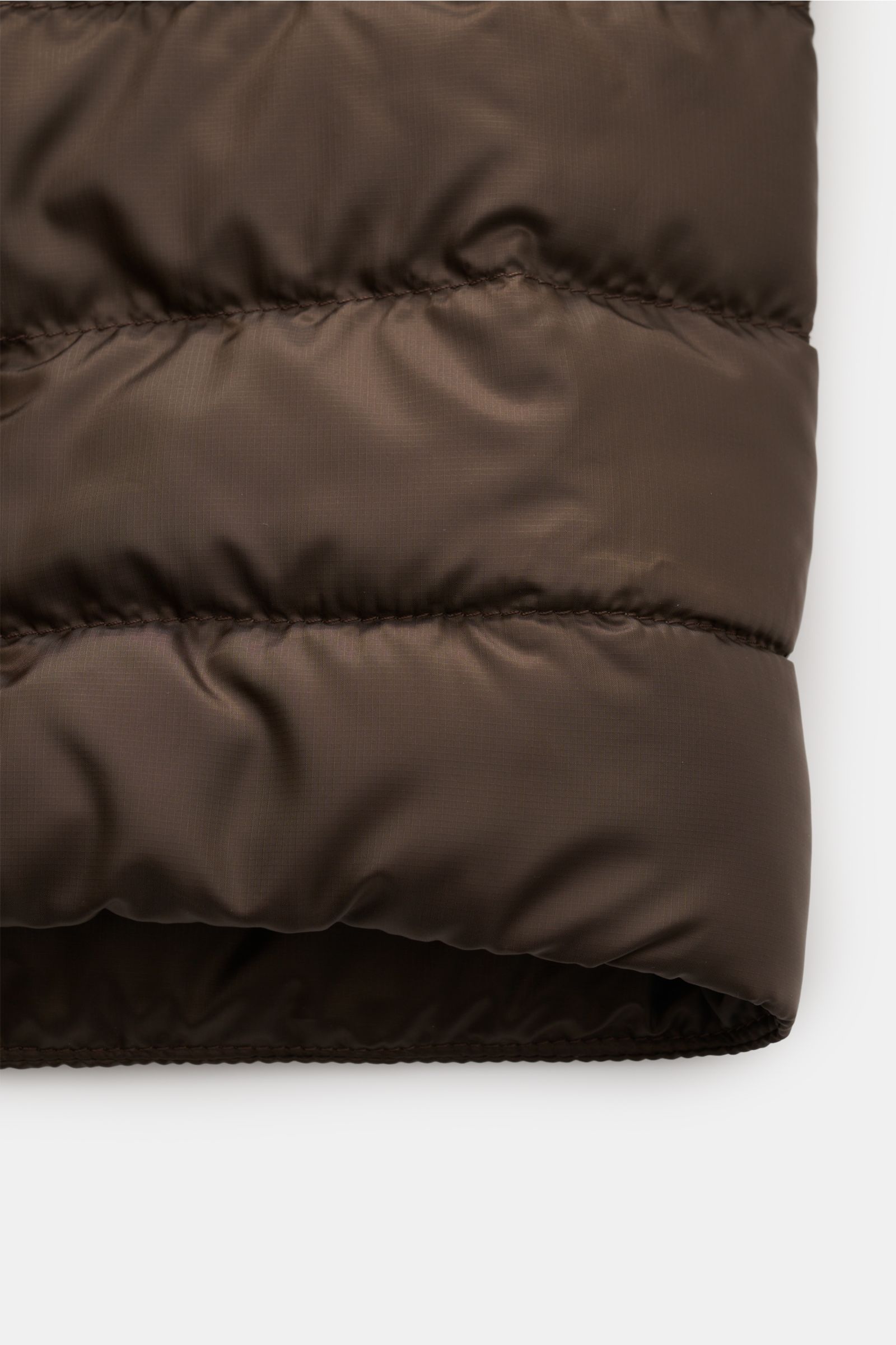 Close-up view of the Canada Goose Down jacket 'Stratus Tonal' dark brown showing its smooth, ripstop microfibre fabric with stitched quilted sections. The super lightweight 'Stratus Tonal' down jacket by CANADA GOOSE with high-quality ripstop outer materi