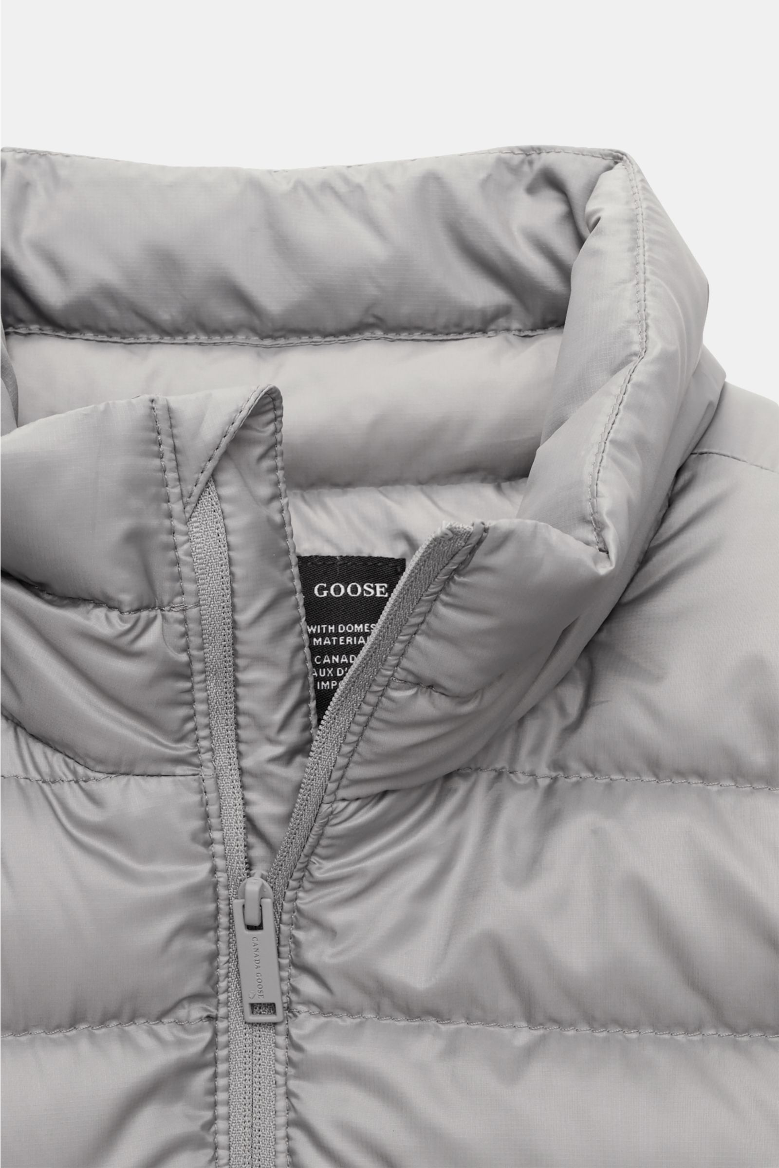 Canada Goose Daunenjacke 'Stratus Tonal' hellgrau, frontale Nahaufnahme des wattierten Stehkragens mit Ripstop-Obermaterial, Reißverschluss und tonalen Details.