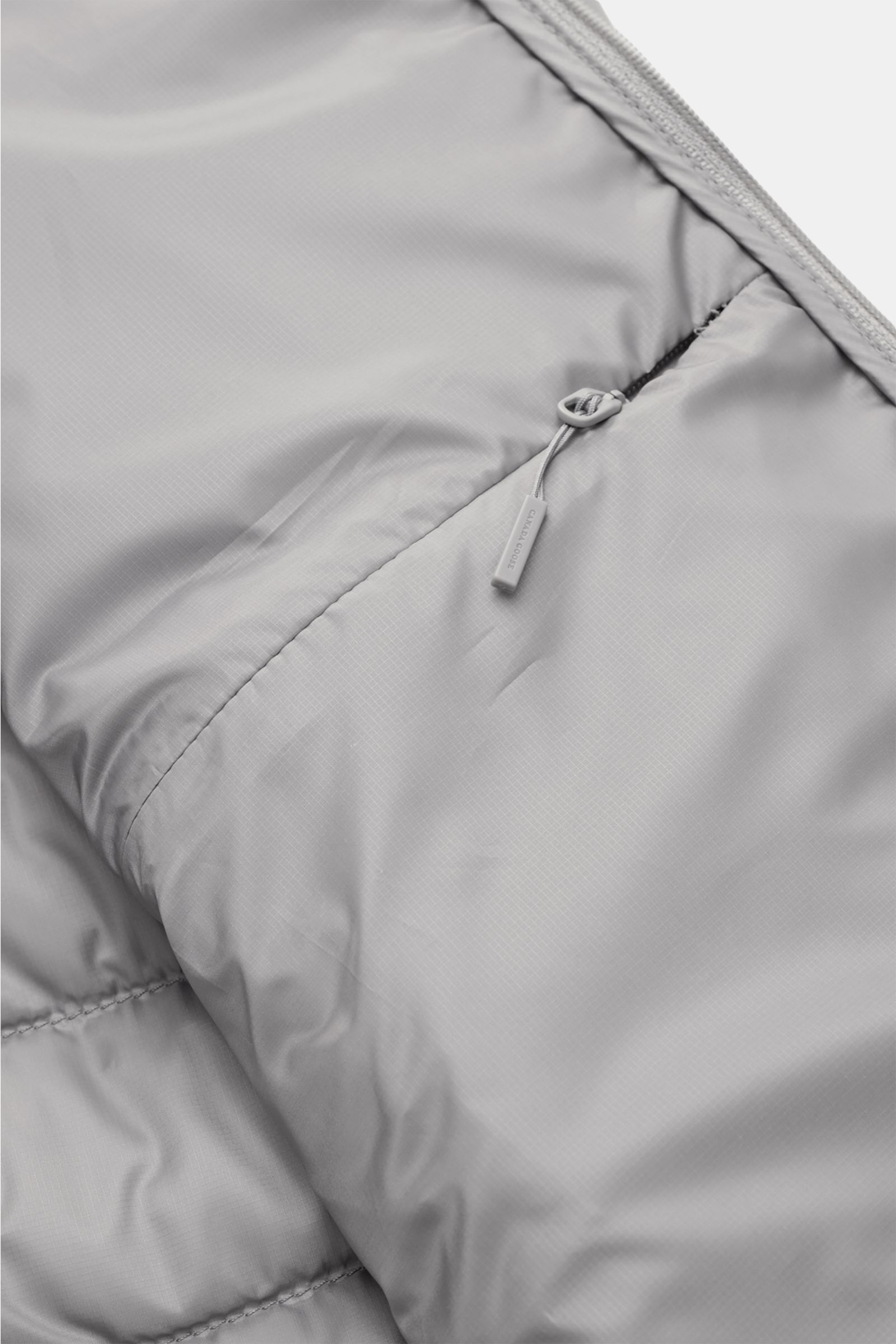 Innenansicht der Canada Goose Daunenjacke 'Stratus Tonal' hellgrau mit Ripstop-Gewebe, Innentasche und Zipper aus glattem, leichtem Material.