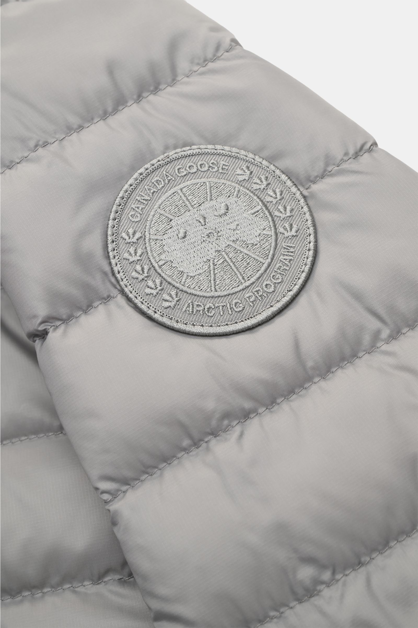 Close-up front sleeve view of the Canada Goose Down jacket 'Stratus Tonal' light grey showing tonal logo patch on ripstop fabric.

The super lightweight 'Stratus Tonal' down jacket by CANADA GOOSE with high-quality ripstop outer material is self-stowin