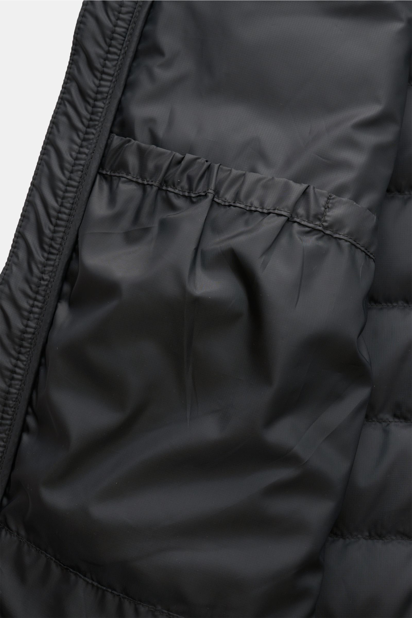 Nahaufnahme der Innentasche der Canada Goose Daunenjacke 'Stratus Hoody' schwarz mit elastischem Saum, hochwertigem Ripstop-Material und tonalem Futter.
