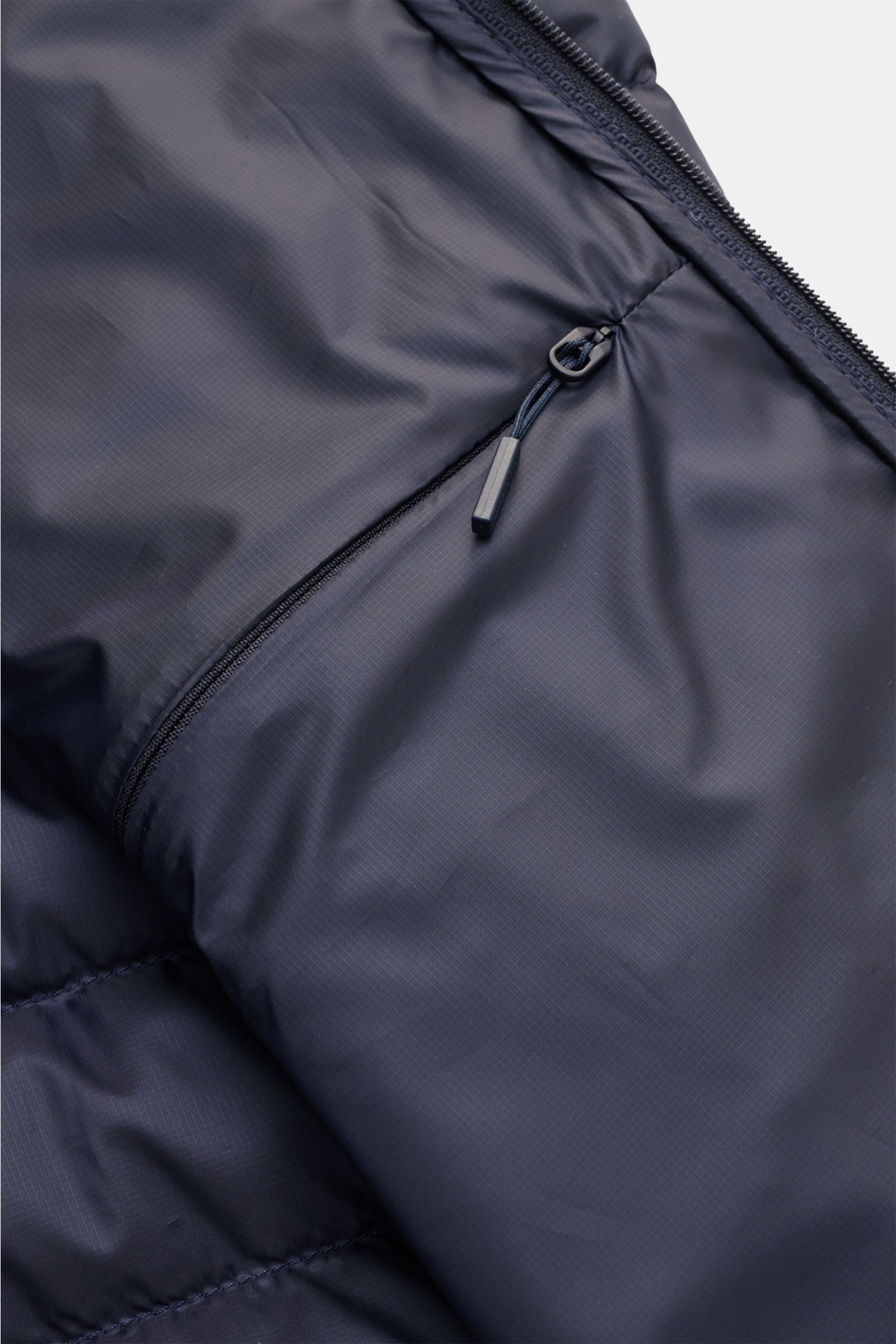 Close-up interior view of the Canada Goose Down jacket 'Stratus Hoody' navy showing the smooth ripstop fabric and zippered inside pocket.

Description: The lightweight down jacket 'Stratus Hoody' by CANADA GOOSE with high-quality ripstop outer material is