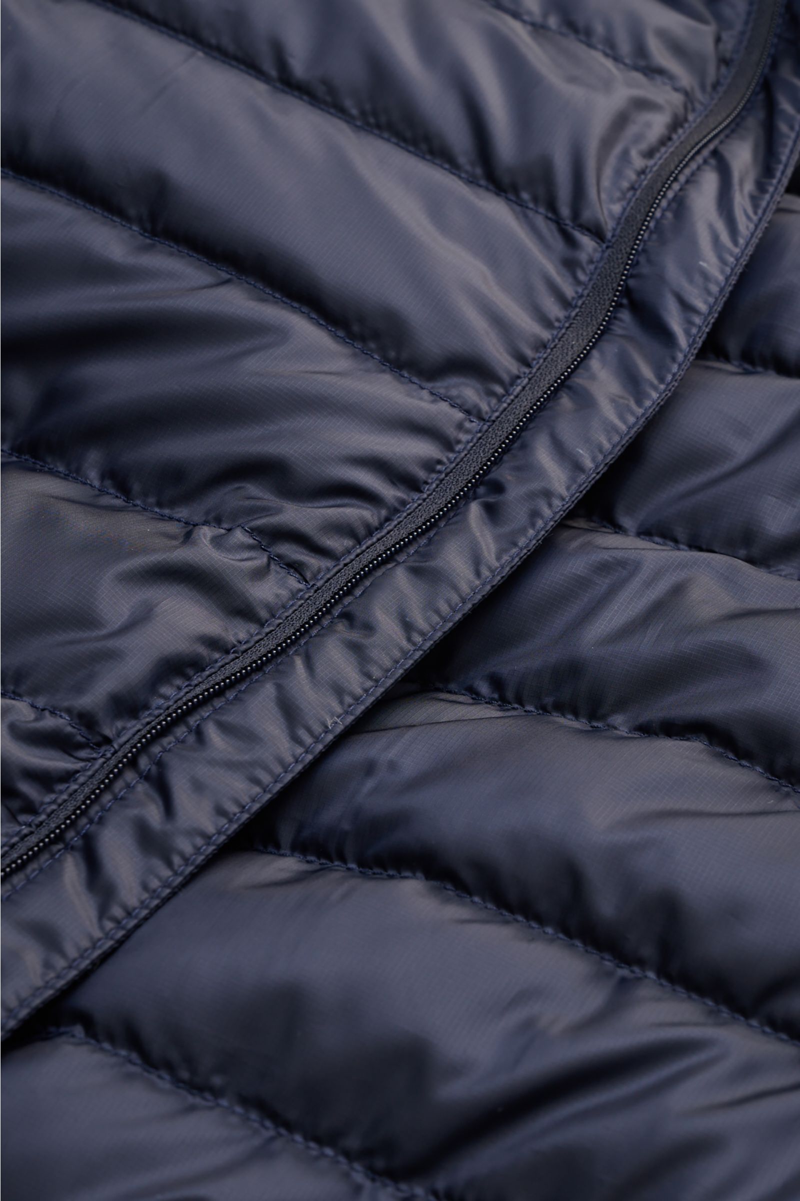 Close-up front view of the navy Canada Goose Down jacket 'Stratus Hoody' showing ripstop fabric with smooth, wind and water repellent texture and zipper.