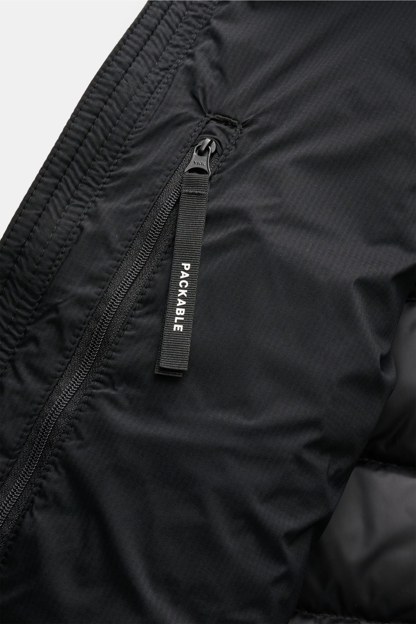 Close-up front-side view of the black Canada Goose Daunenjacke 'Lodge Hoody' showing ripstop microfiber fabric, zipper with 'PACKABLE' pull tab, and detailed stitching. Maximaler Komfort in leichter Ausführung: Die in sich verstaubare Daunenjacke 'Lodge H