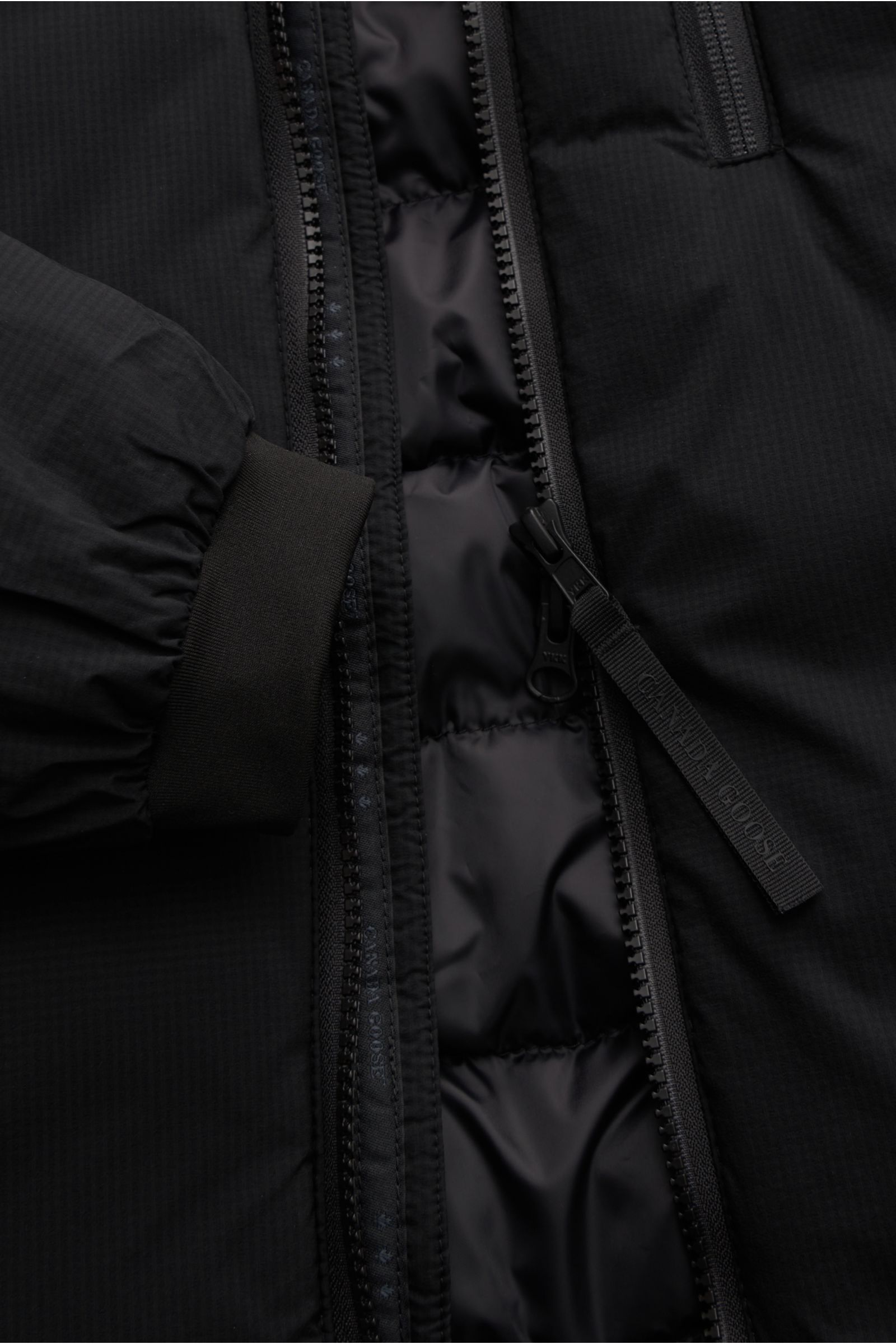 Close-up front view of Canada Goose Daunenjacke 'Lodge Hoody' schwarz showing zipper, cuff, and lightweight, packable down filling.

Maximaler Komfort in leichter Ausführung: Die in sich verstaubare Daunenjacke 'Lodge Hoody' von CANADA GOOSE wird mit w