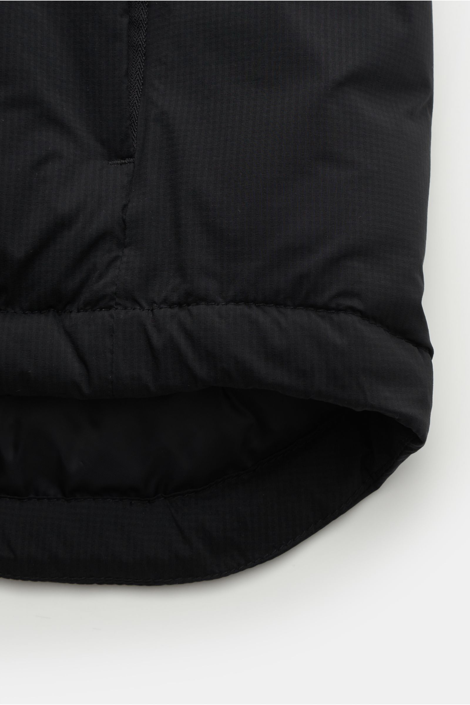 Close-up from below of the hem and stitching detail of the Canada Goose Daunenjacke 'Lodge Hoody' schwarz in black ripstop fabric with lightweight down filling.

Maximaler Komfort in leichter Ausführung: Die in sich verstaubare Daunenjacke 'Lodge Hoody