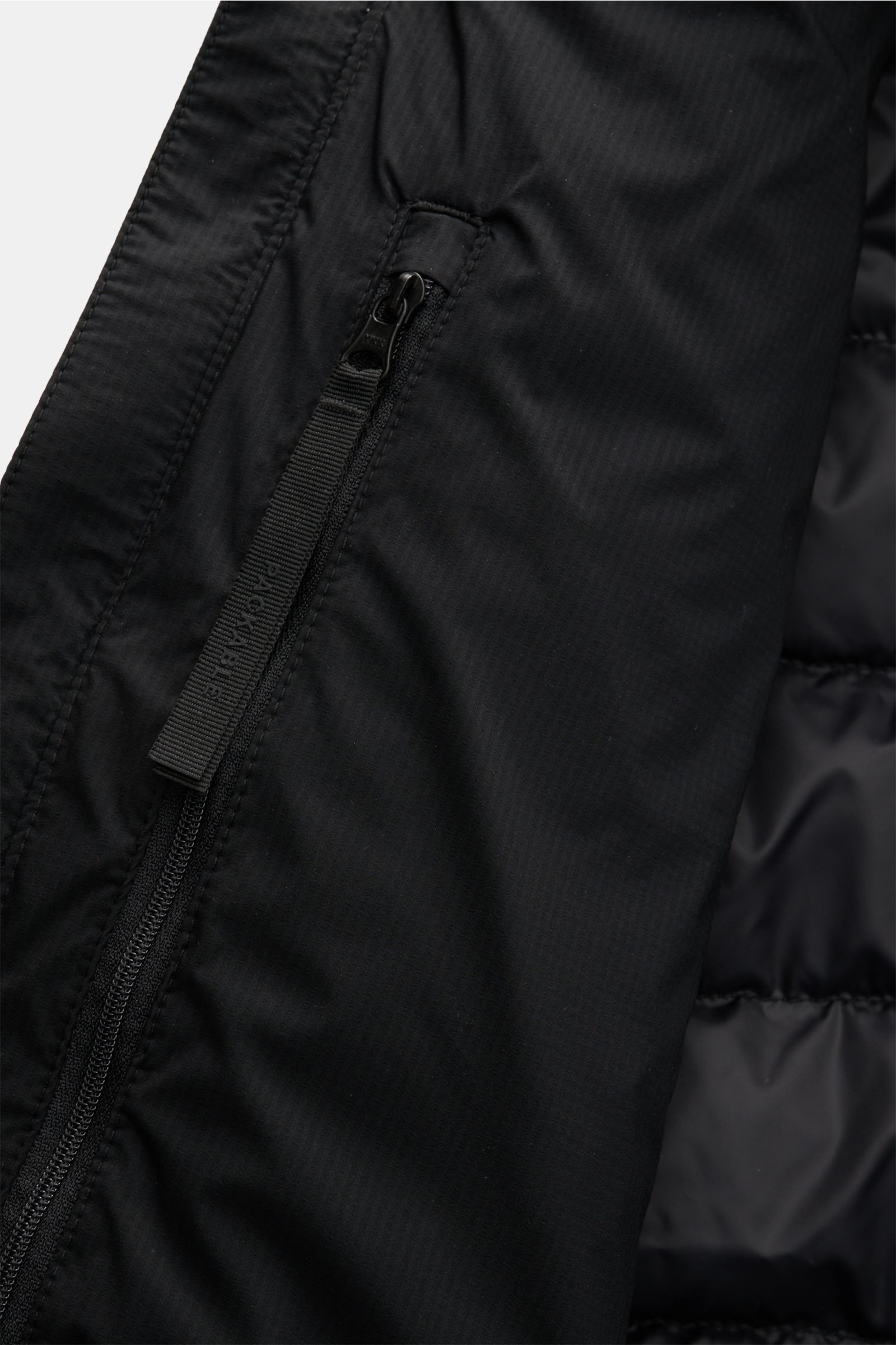 Close-up front angle of the Canada Goose Daunenjacke 'Lodge Hoody' schwarz showing black ripstop fabric, zipper, and quilted lining; Maximaler Komfort in leichter Ausführung: Die in sich verstaubare Daunenjacke 'Lodge Hoody' von CANADA GOOSE wird mit w