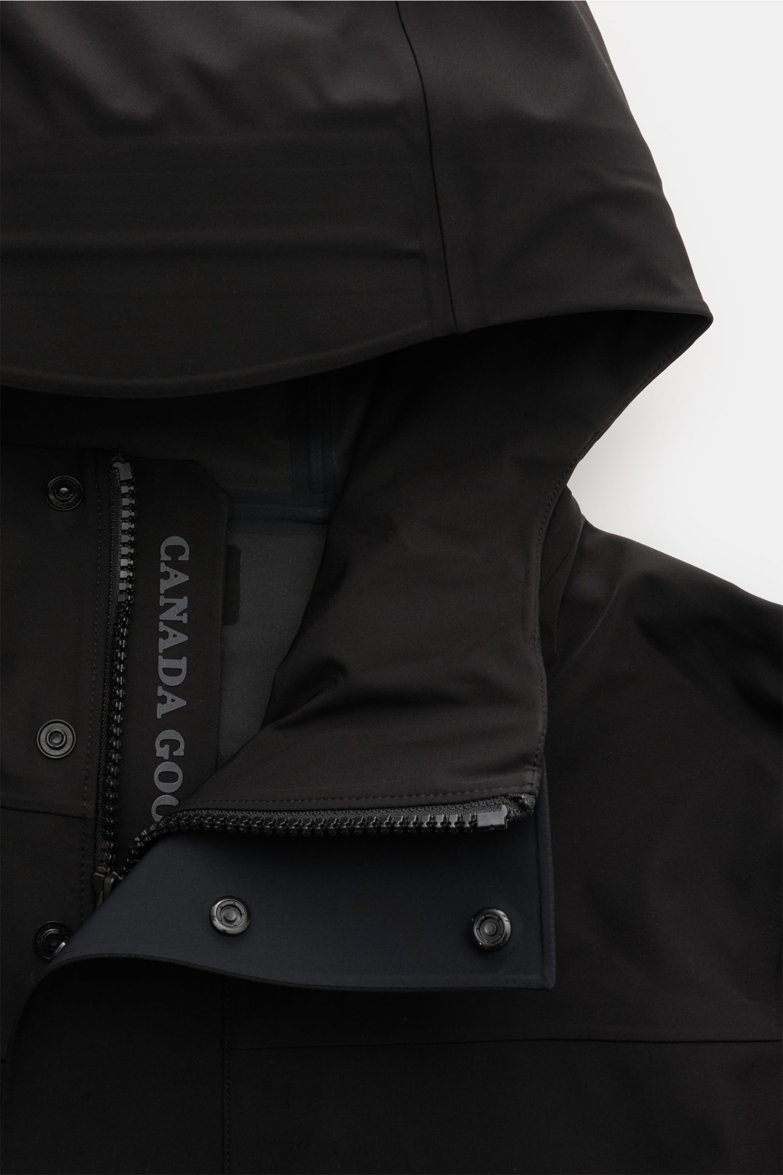 Nahaufnahme der Kapuze und des Zwei-Wege-Reißverschlusses der schwarzen Canada Goose Jacke 'Rupert' mit wasserdichtem, glattem Microfaserstoff.