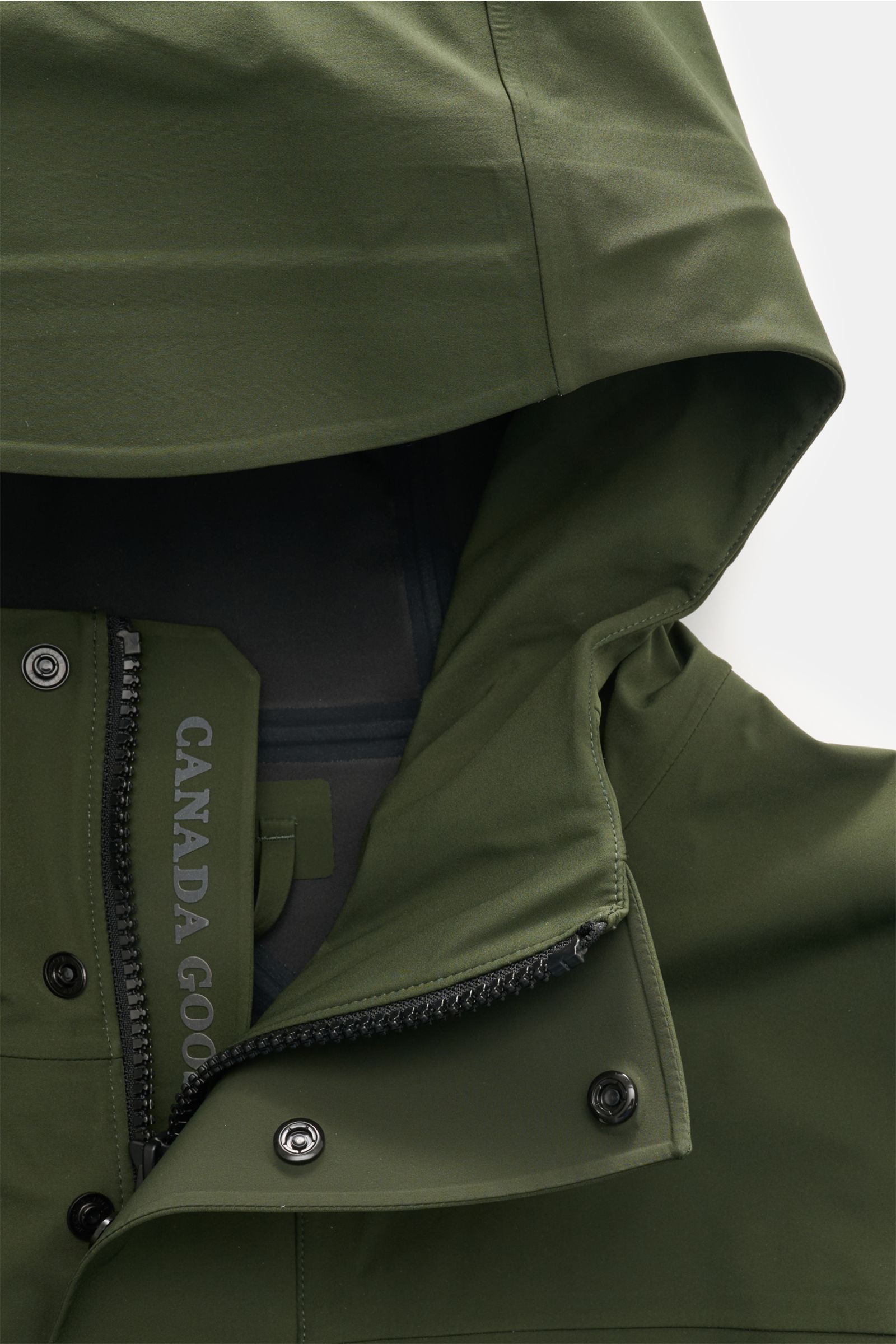 Nahaufnahme der Kapuze und des Zwei-Wege-Reißverschlusses der Canada Goose Jacke 'Rupert' dunkelgrün aus hochwertiger, wasserdichter Microfaser mit glattem Griff.