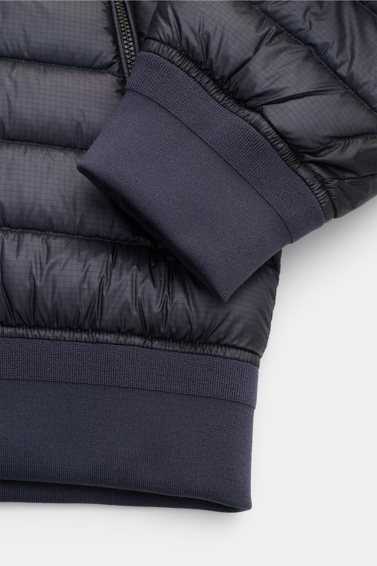 Nahaufnahme des Ärmel- und Saumabschlusses des C.P. Company Daunenblouson dark navy mit wasserabweisender Ripstop-Oberfläche und elastischem Bündchen.