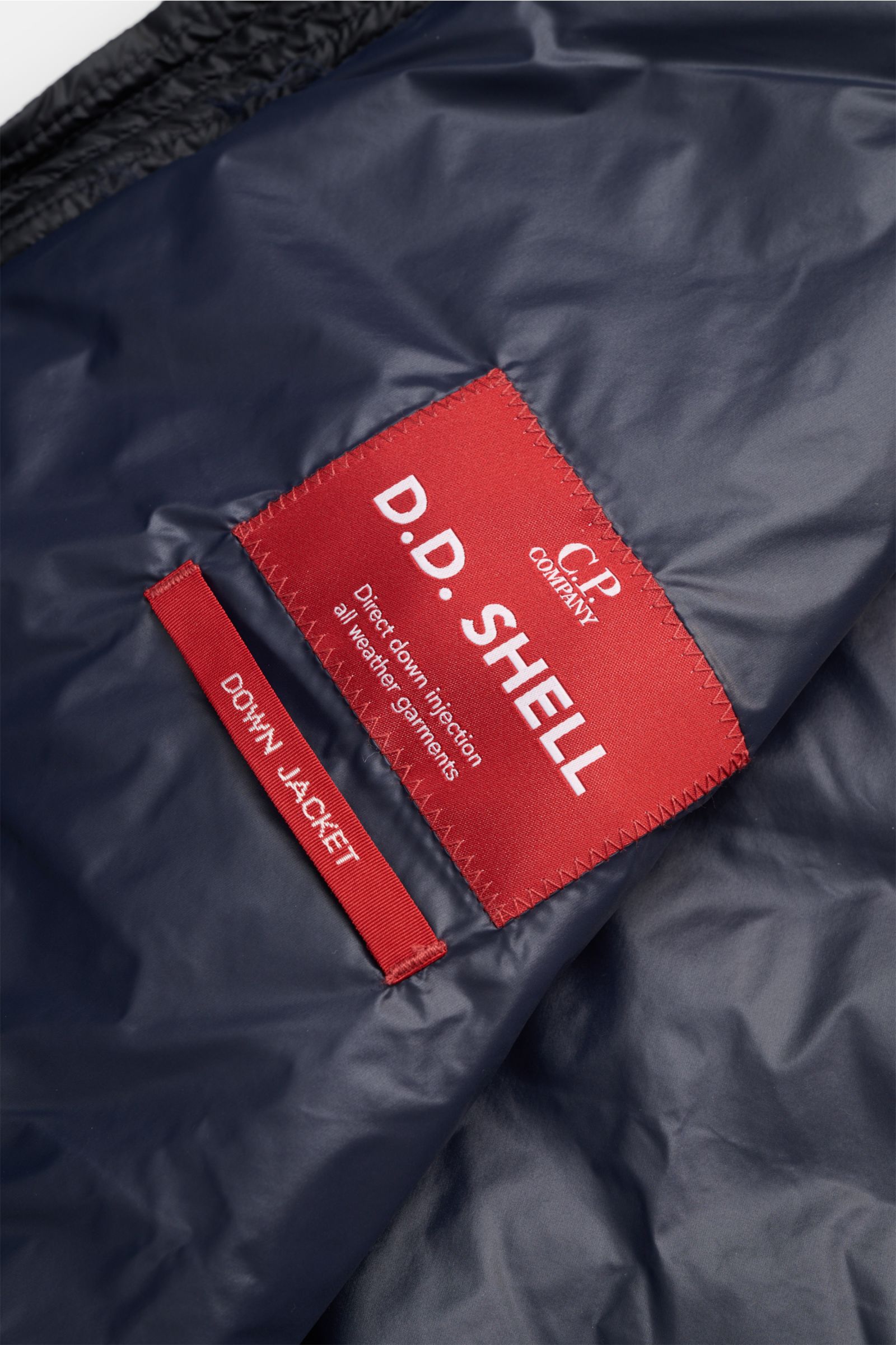 C.P. Company Daunenblouson dark navy von innen in Nahaufnahme, wasserabweisende Ripstop-Microfaser mit rotem D.D. Shell Label.