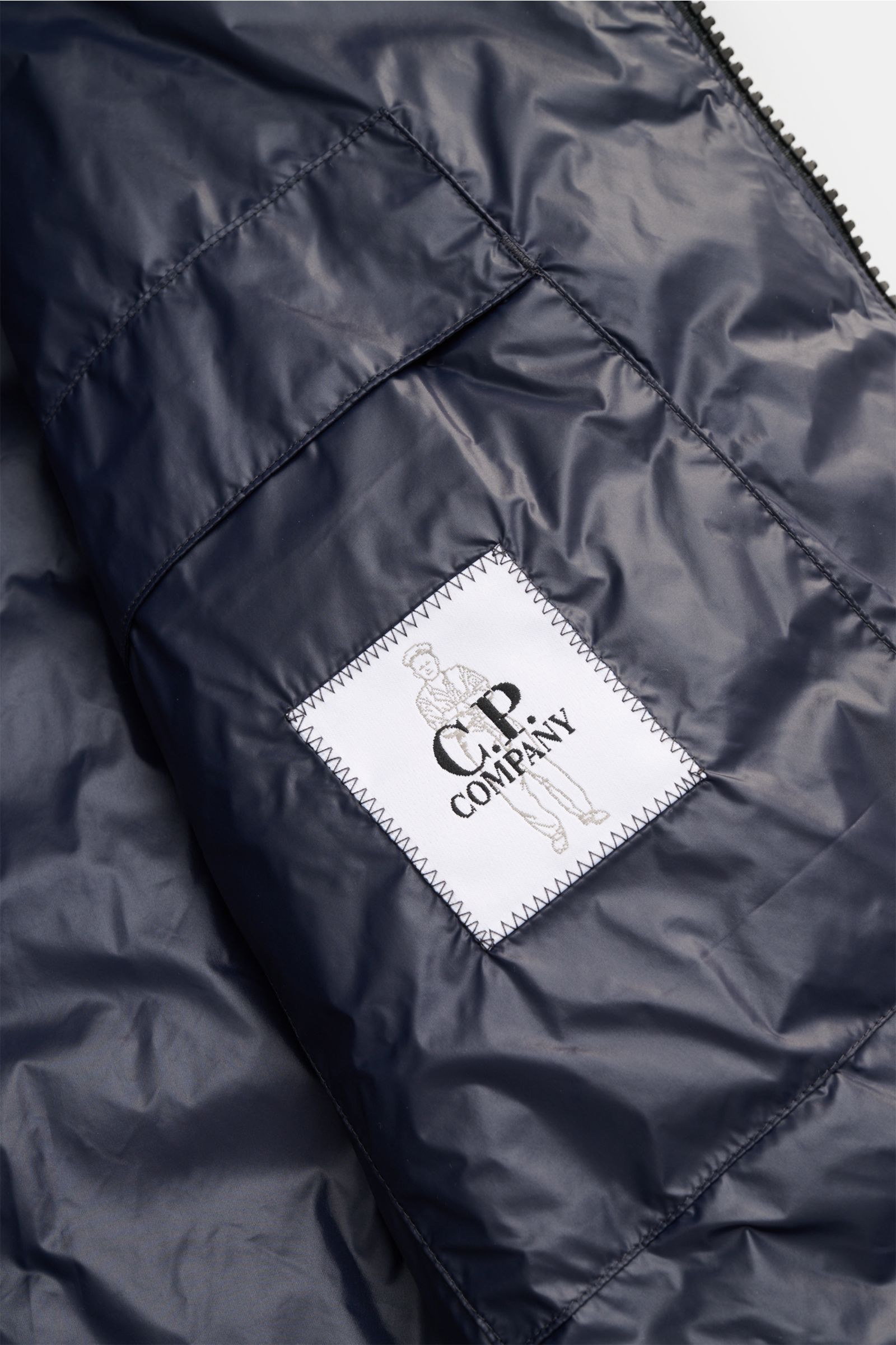 C.P. Company Daunenblouson dark navy Innenansicht mit wasserabweisender Ripstop-Oberfläche, Innentasche und Markenlabel in Nahaufnahme.