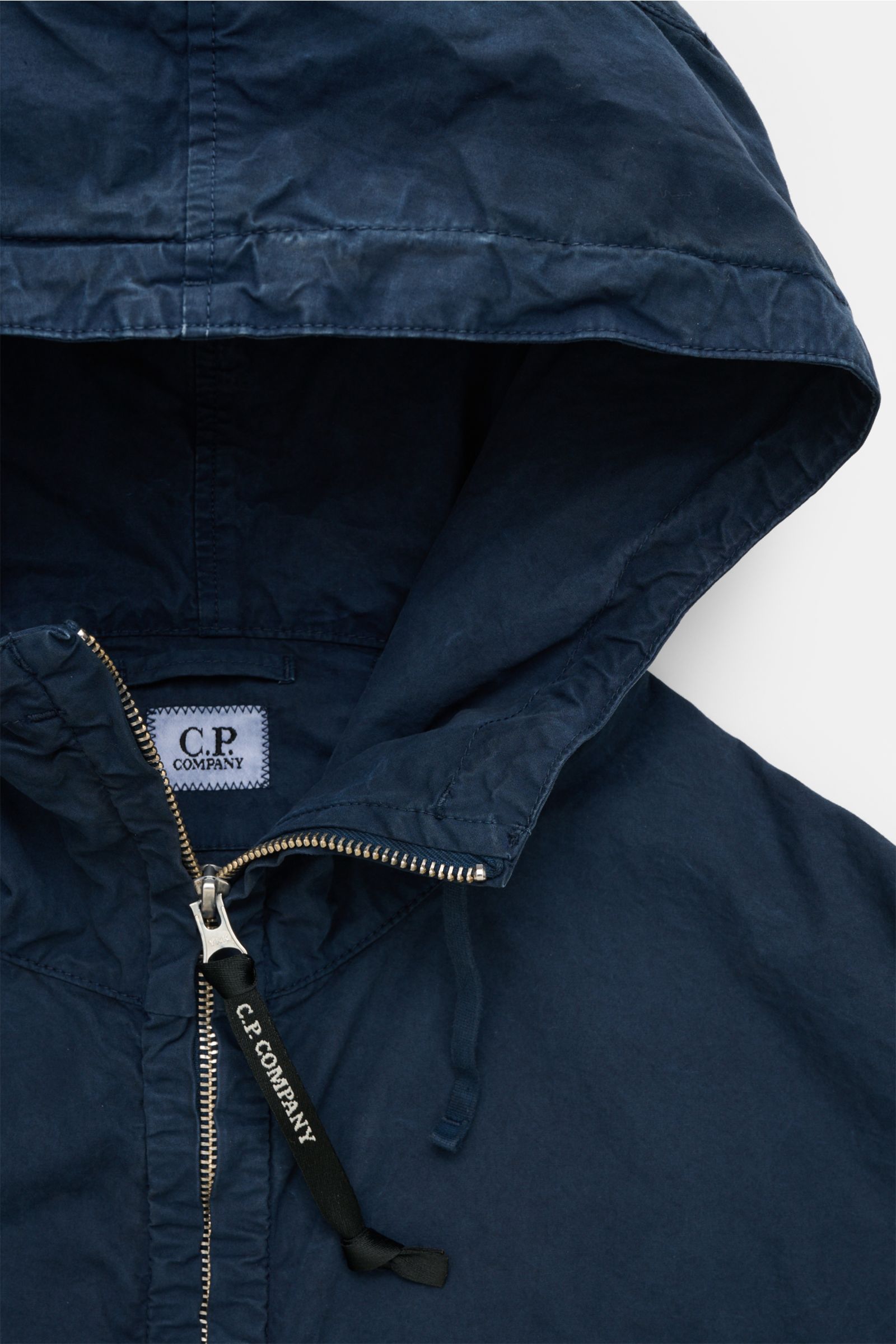 Close-up front view of the C.P. Company Jacket navy hood and zipper, showing the garment-dyed pure cotton Micro-Reps fabric with a soft, compact texture. Effortlessly urban: This new jacket with hood from C.P. COMPANY is made of Micro-Reps, a high-density