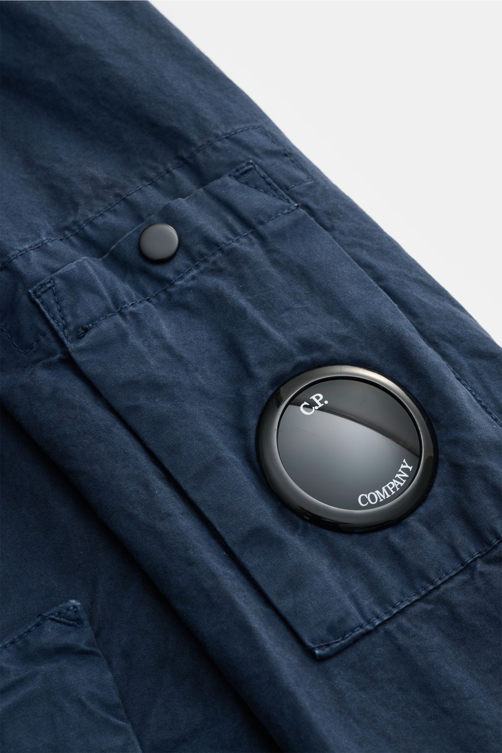 Nahaufnahme der C.P. Company Jacke navy aus Micro-Reps-Baumwolle, Detailansicht der Ärmel-Tasche mit Logo-Brille, schräge Naht.