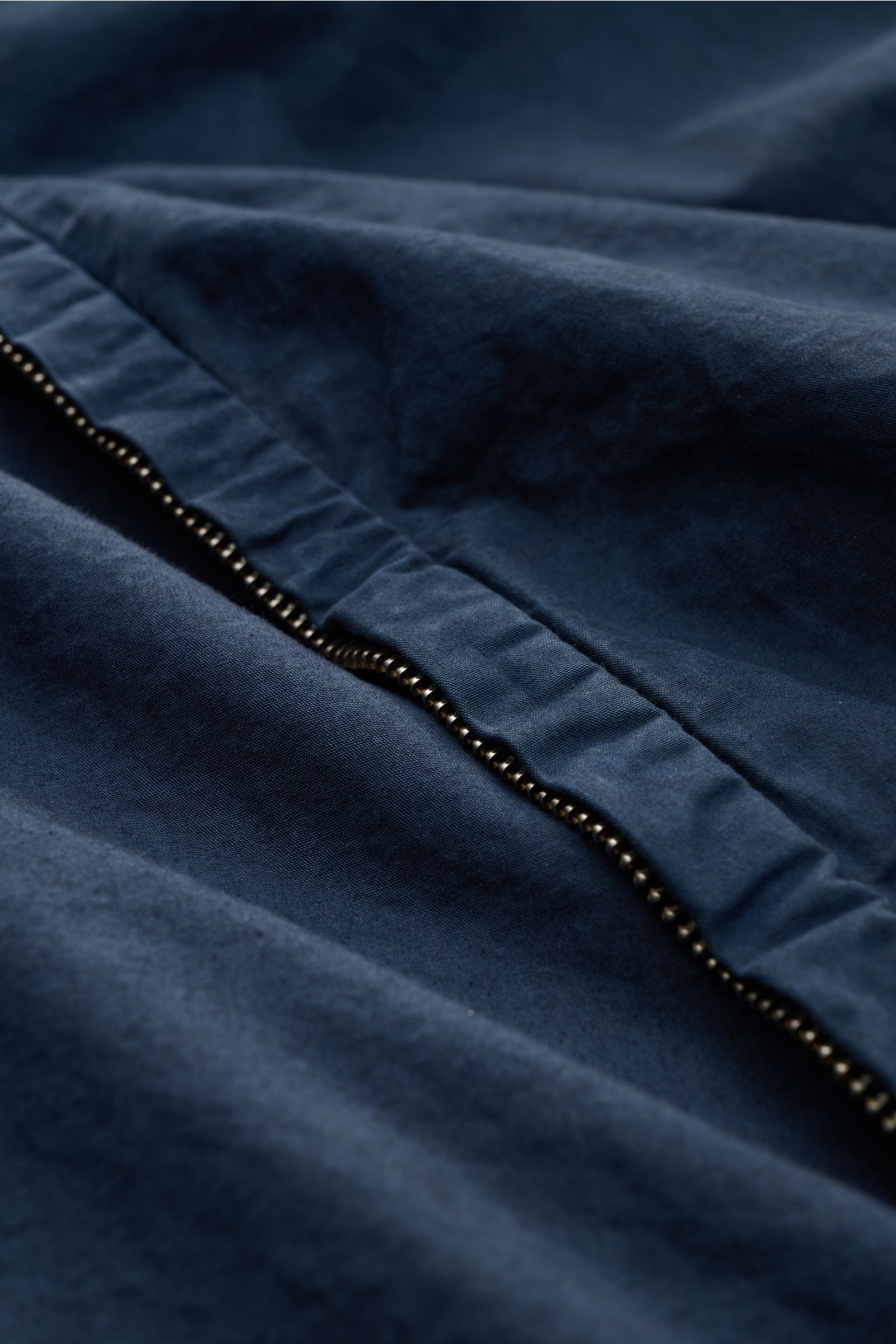 Nahaufnahme der Metallreißverschluss-Detailaufnahme der C.P. Company Jacke navy aus weicher, garment dyed Baumwolle in Slim Fit, Kapuze mit Tunnelzug.