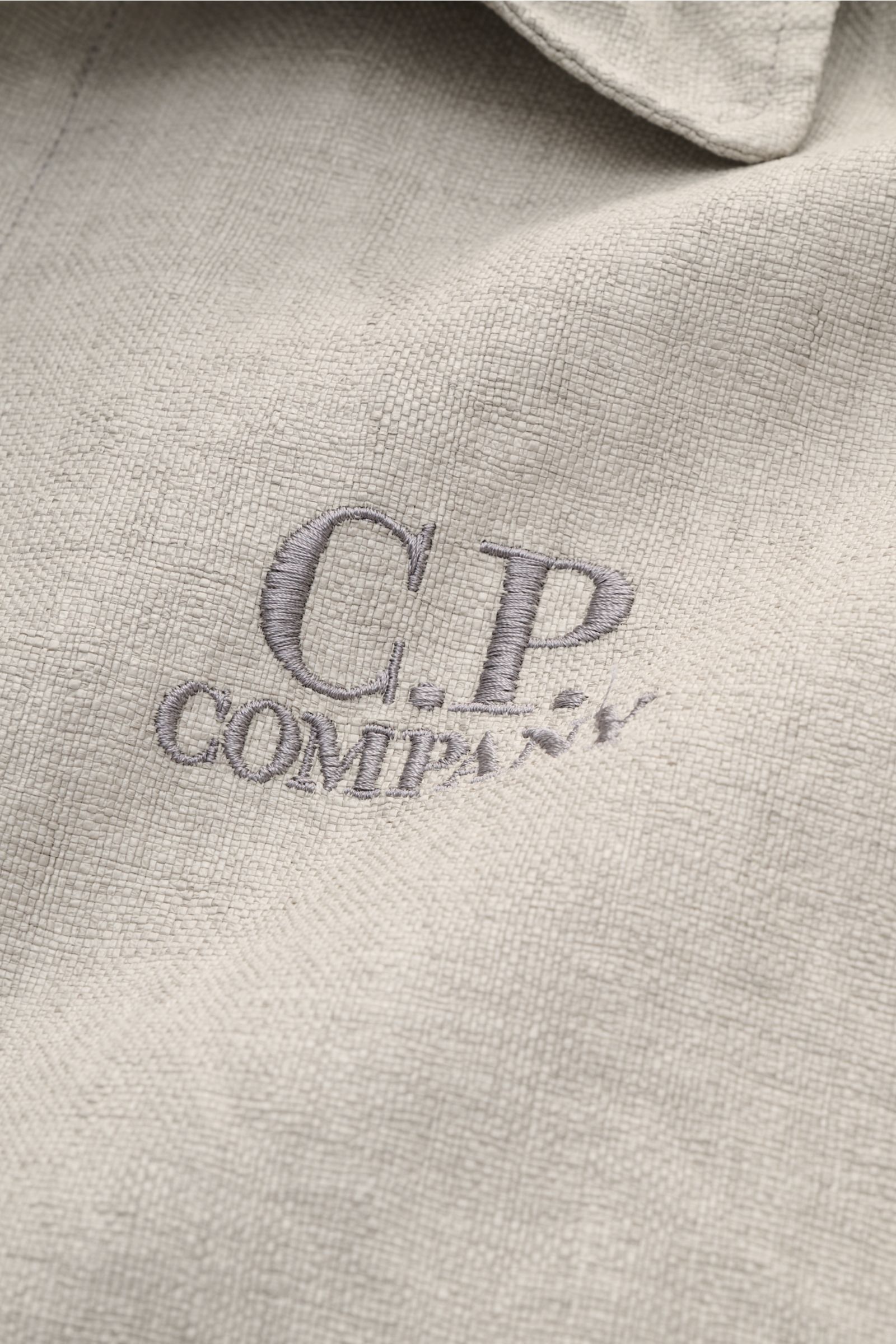 Close-up front view of C.P. Company Jacket 'Goggle Jacket' grey showing textured high-quality microfibre fabric and embroidered logo.

Signature design from C.P. COMPANY: The 'Goggle Jacket' makes a futuristic statement with its goggle lenses integrate