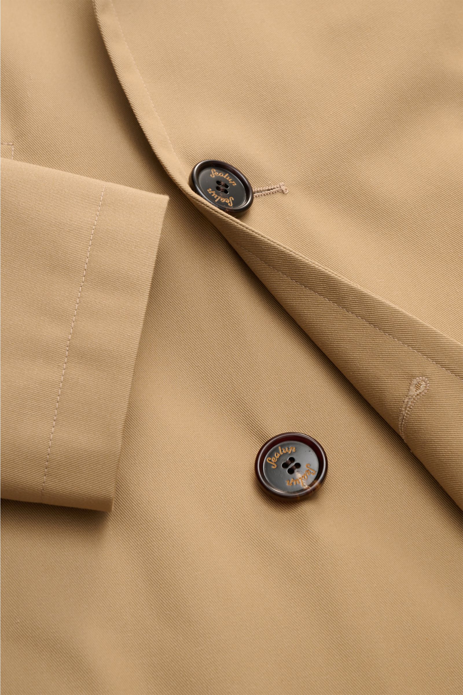 Close-up front detail of Sealup Pea coat 'Amalfi' beige, showing buttons and fabric texture from a top-down perspective. Get the look of a Hanseatic merchant with the elegant pea coat 'Amalfi' by traditional label SEALUP: made of lightweight twill in a ba