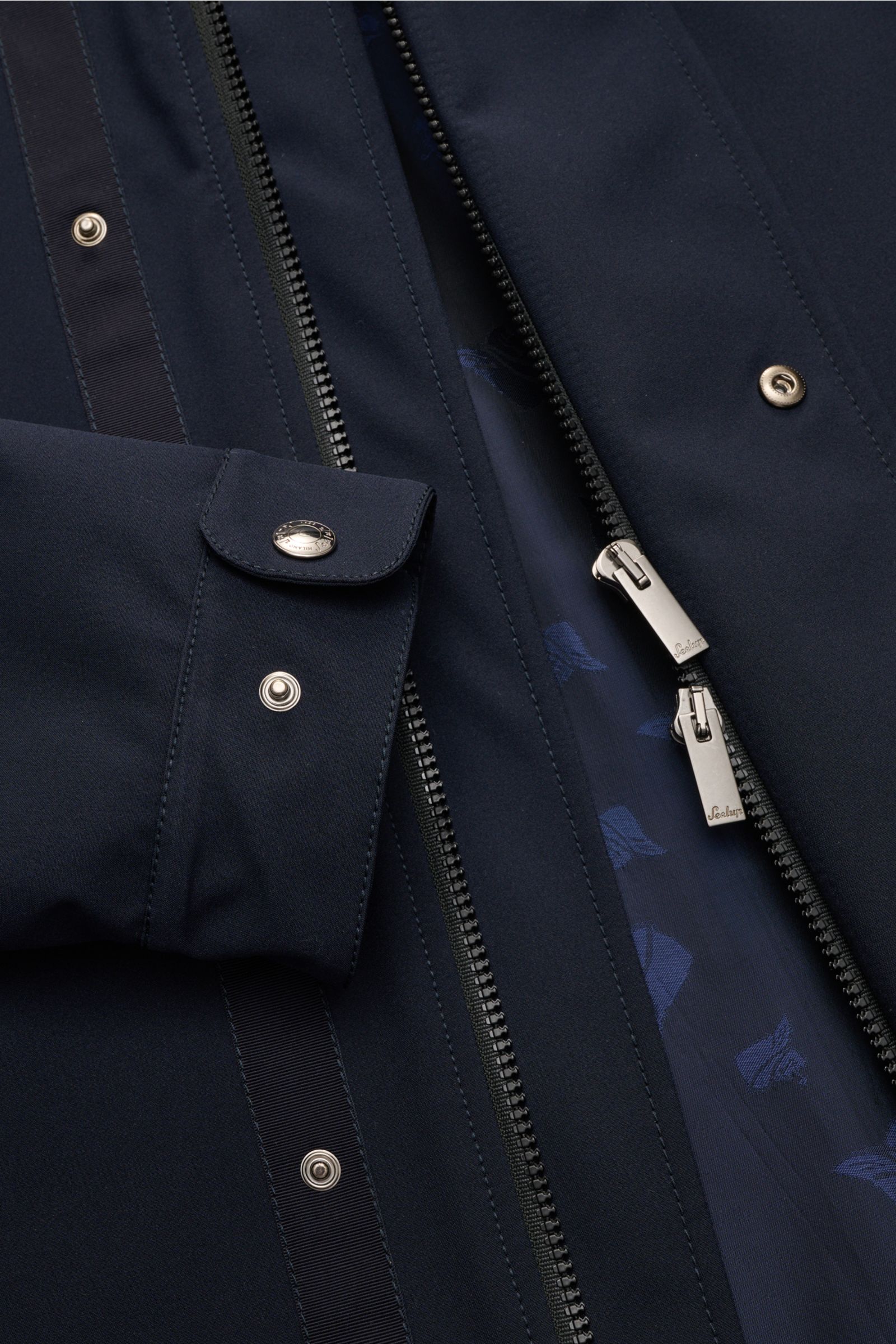 Nahaufnahme des Sealup Parka 'Hurricane' navy von schräg oben, zeigt Reißverschluss, Druckknöpfe und Ärmel mit Knopf.