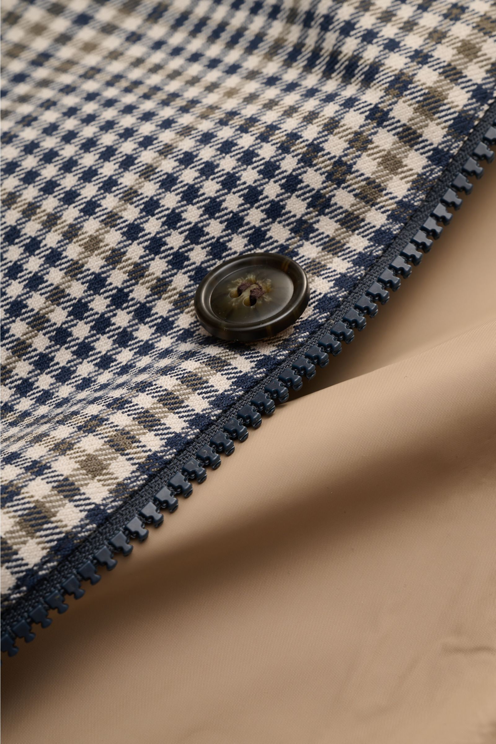 Close-up front view of Barbour Rain coat 'Check Rokig' navy/olive checked showing microfibre fabric, button, zipper, and beige smooth lining. Be ready for changeable weather with the lightweight rain coat 'Check Rokig' by BARBOUR, which has been given a w