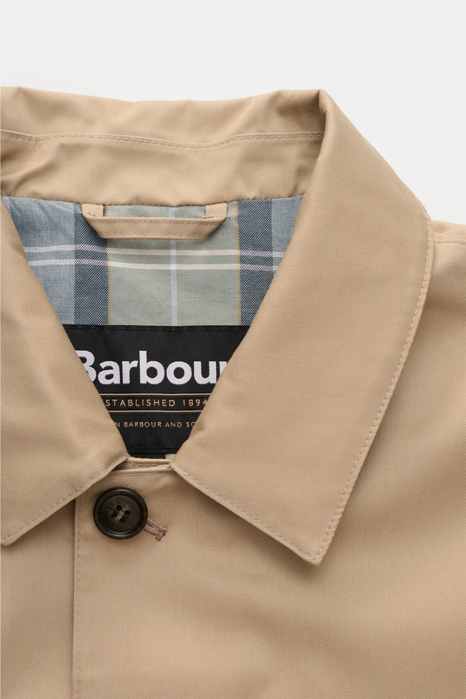 Close-up front view of the collar and button of the Barbour Rain coat 'Rokig' beige, featuring high-quality microfiber with viscose, a soft feel, waterproof coating, slim fit, two-way zip, storm flap with buttons, turn-down collar, large welt pockets, cen