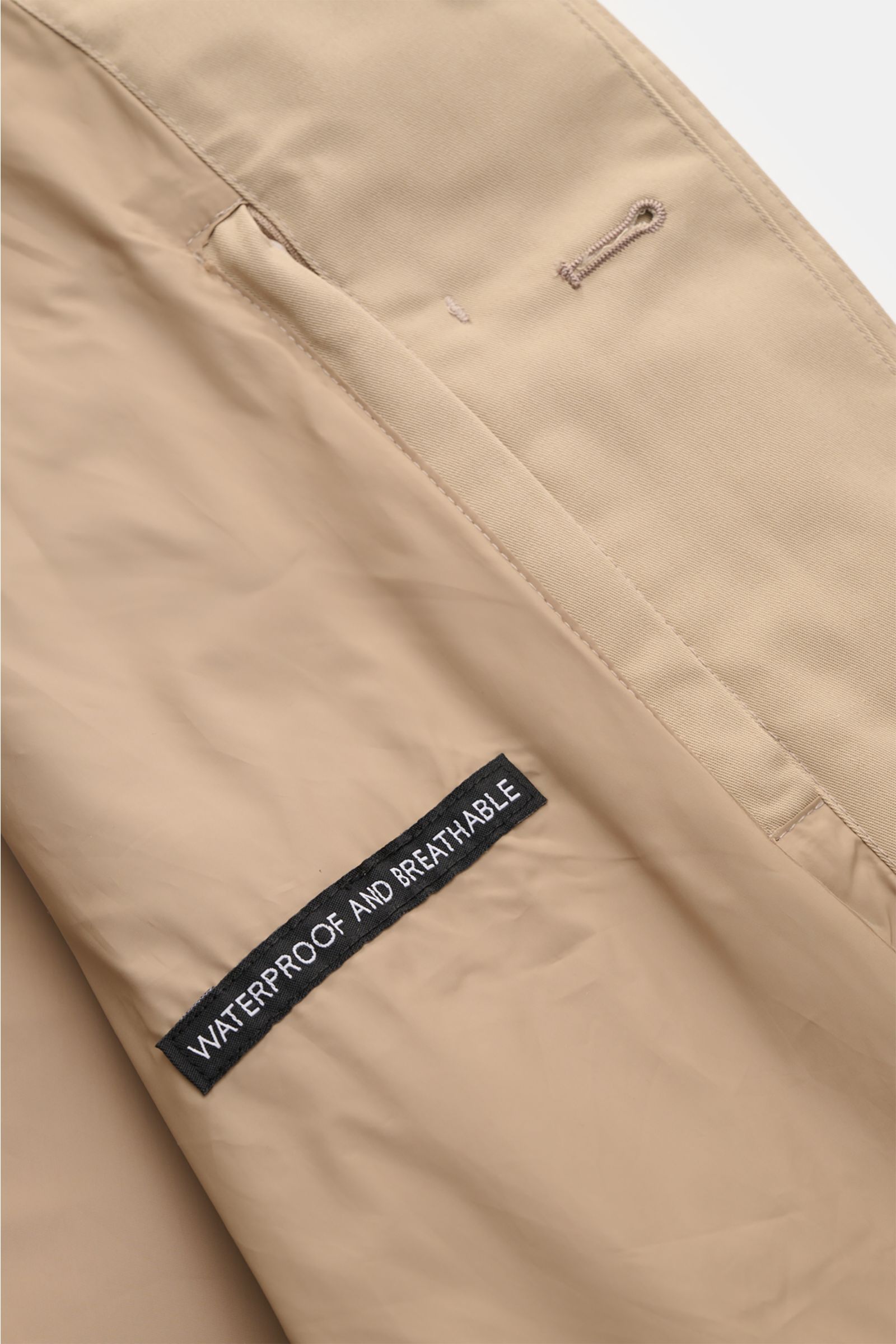 Close-up interior view of the Barbour Rain coat 'Rokig' beige showing the waterproof and breathable membrane label and stitching details. Be ready for changeable weather with the lightweight rain coat 'Check Rokig' by BARBOUR, which has been given a water