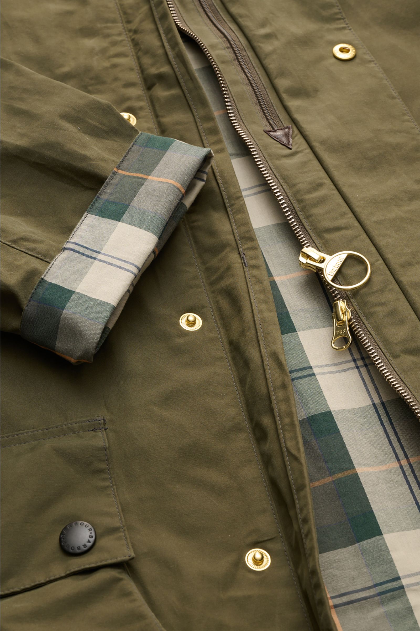 Close-up front view of Barbour Waxed jacket 'Icons Border Casual' olive, showing waxed cotton fabric, two-way zip, snap buttons, and signature tartan lining.

Perfectly equipped for the transitional season: The waxed jacket 'Border' combines dependable