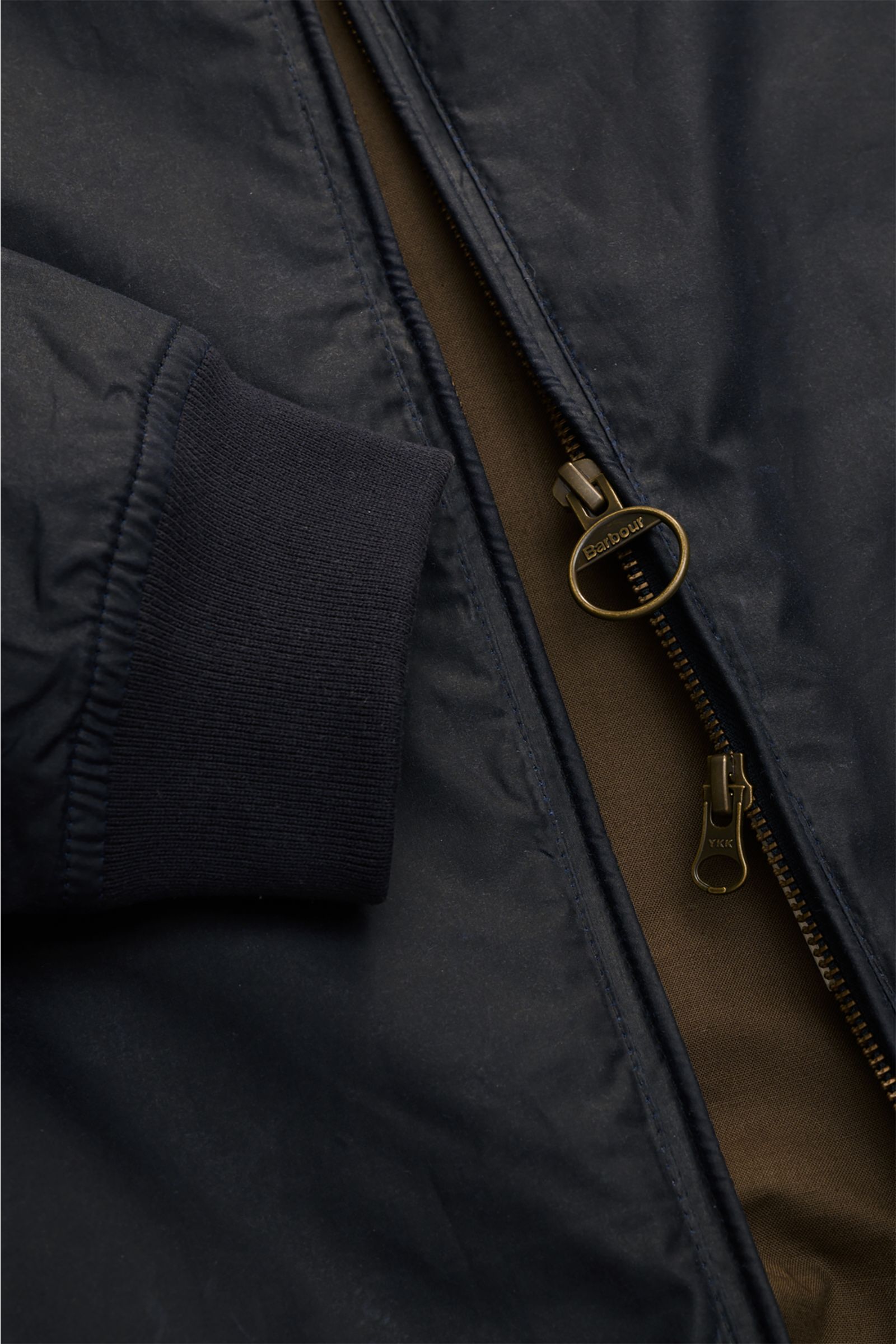 Close-up front view of Barbour Waxed blouson 'Royston' dark navy showing sleeve cuff and brass zipper with ring pull.

Classic blouson by traditional label BARBOUR: With its short cut and signature corduroy trim on the collar, the model 'Royston' in wa