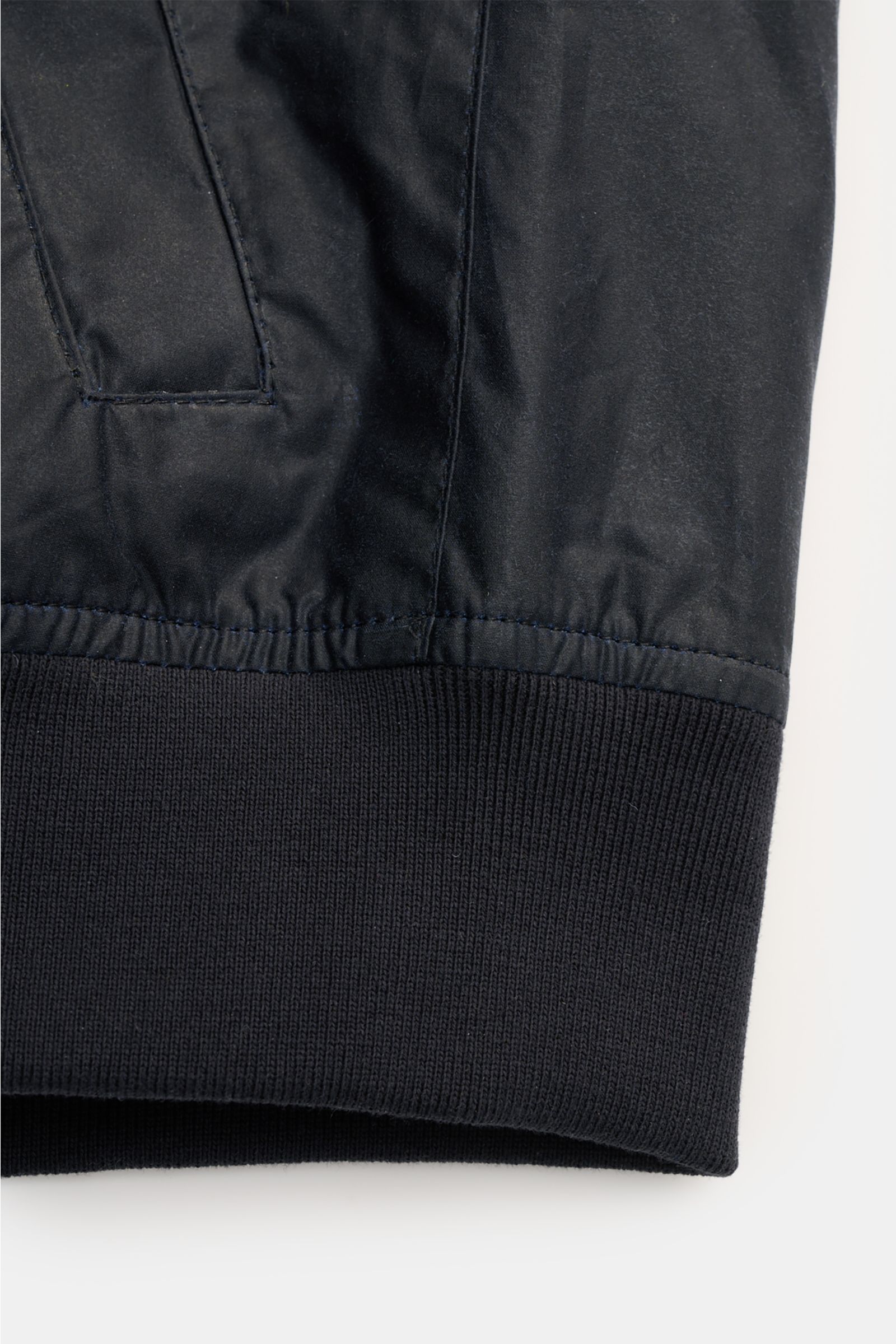 Close-up of the lower section of the Barbour Waxed blouson 'Royston' dark navy, showing the elasticated ribbed hem, waxed cotton fabric, and slanted hip pocket, photographed from the front.

Description: 
Classic blouson by traditional label BARBOUR: W