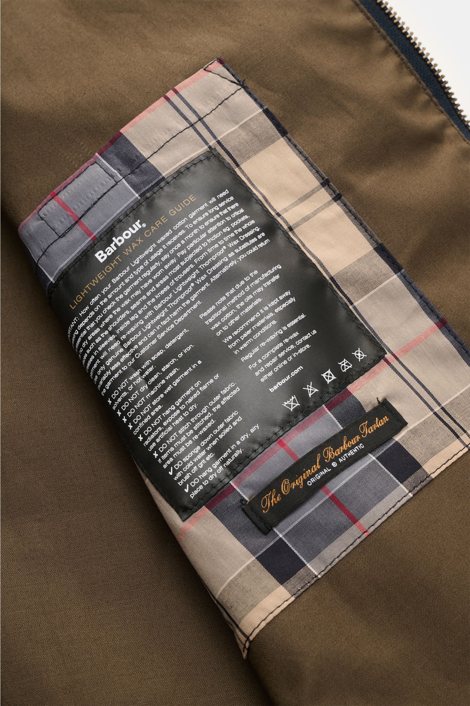 Close-up interior view of the Barbour Waxed blouson 'Royston' dark navy showing the tartan lining and care label on waxed cotton fabric.

Classic blouson by traditional label BARBOUR: With its short cut and signature corduroy trim on the collar, the mo