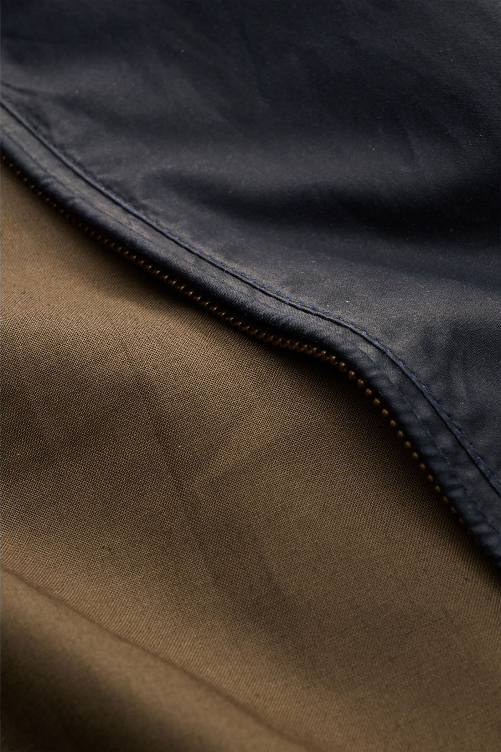 Close-up of the Barbour Waxed blouson 'Royston' dark navy showing the waxed cotton fabric, zipper, and lining from a top-down perspective.

Description: Classic blouson by traditional label BARBOUR: With its short cut and signature corduroy trim on the