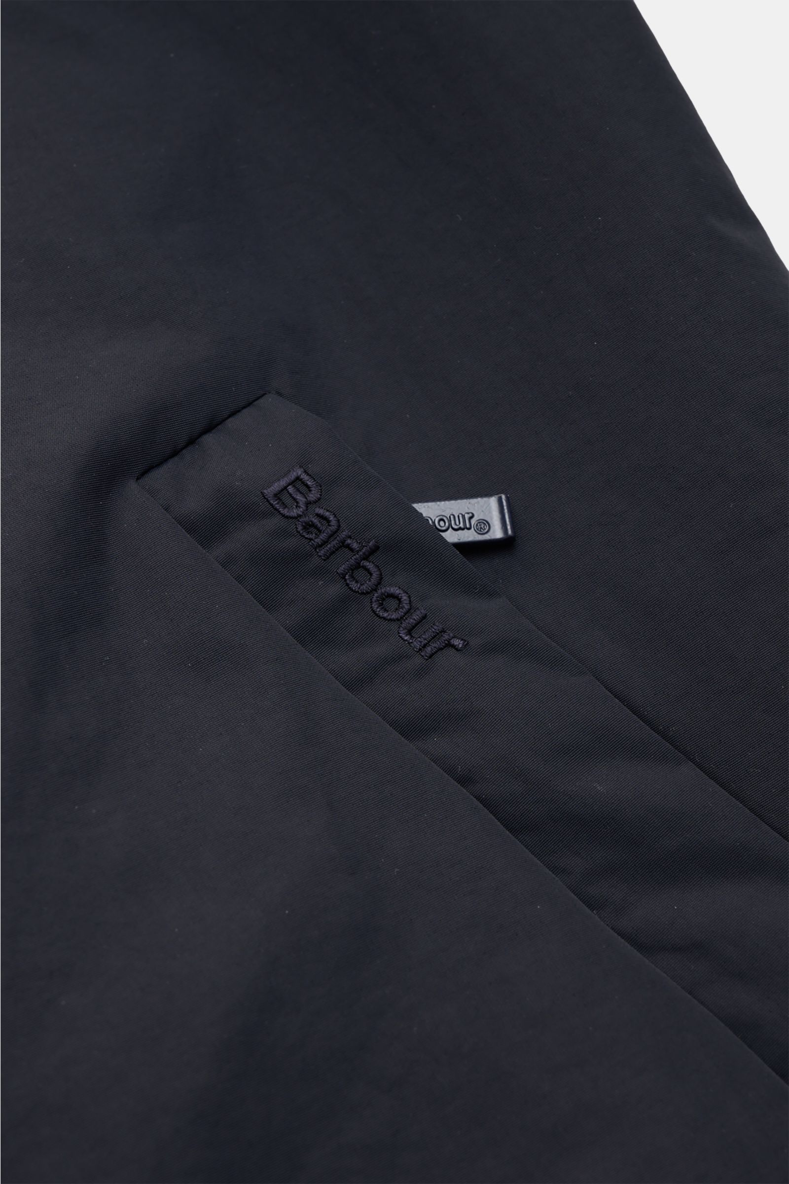 Close-up front view of Barbour Blouson 'Royston' navy with embroidered logo on high-quality microfibre fabric, showing slim fit and zip pocket.

Description: Modern blouson by traditional label BARBOUR: With its short cut and signature corduroy trim on